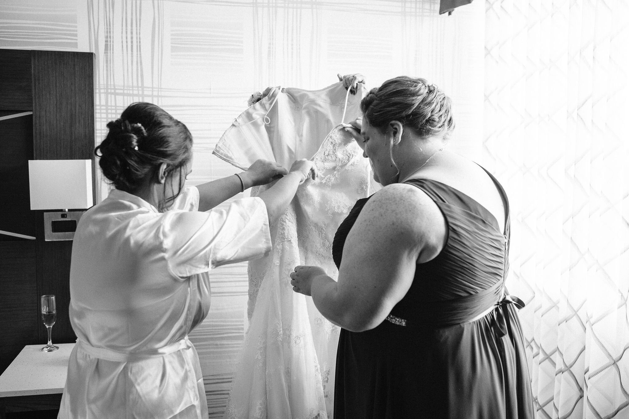 Bride and bridesmaid getting her wedding dress