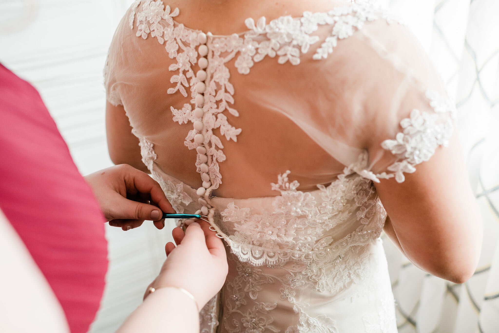 Bride's mom buttoning up bride's wedding dress