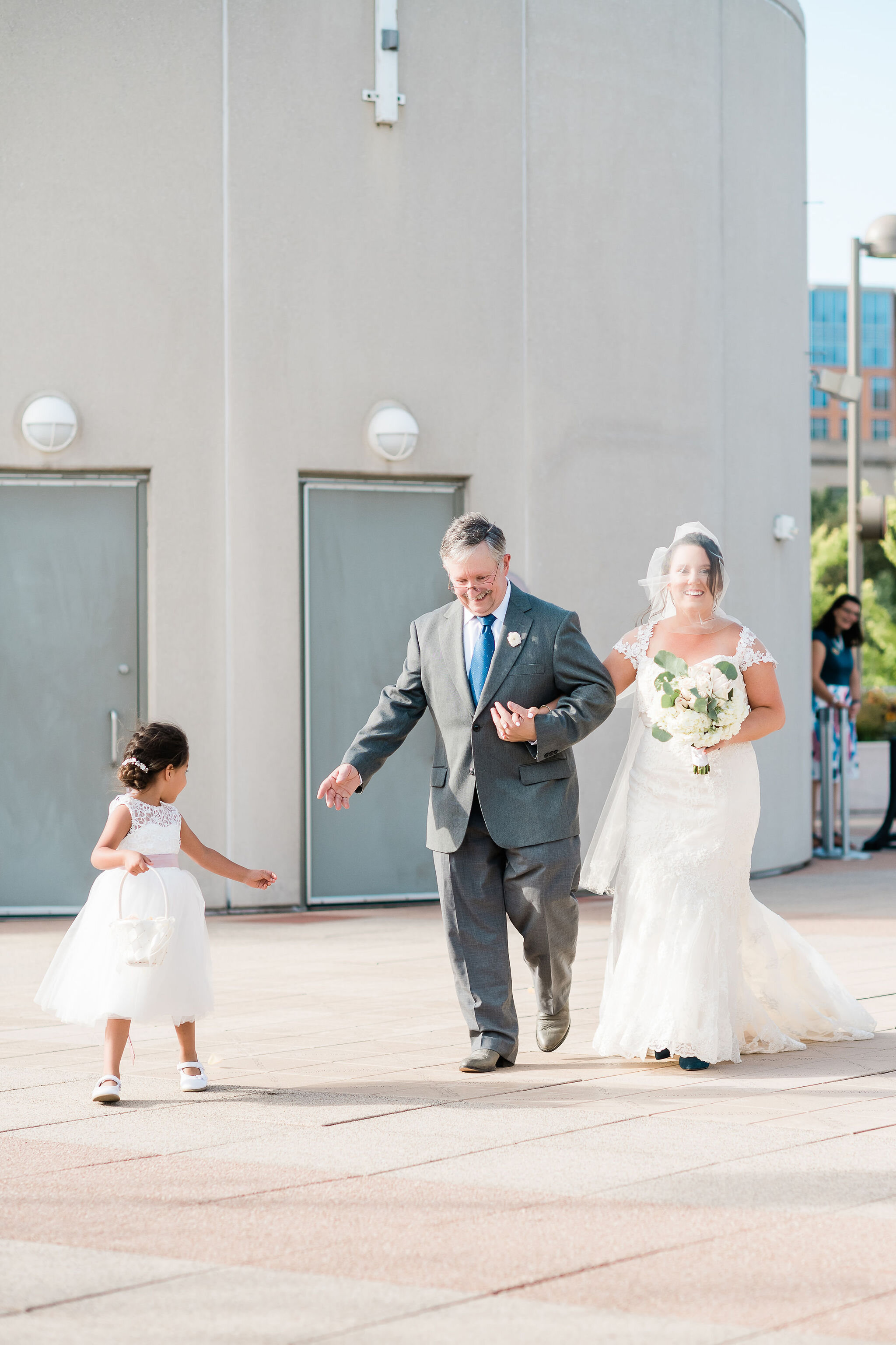 Bride and her father and the flower girl walking down the aisle