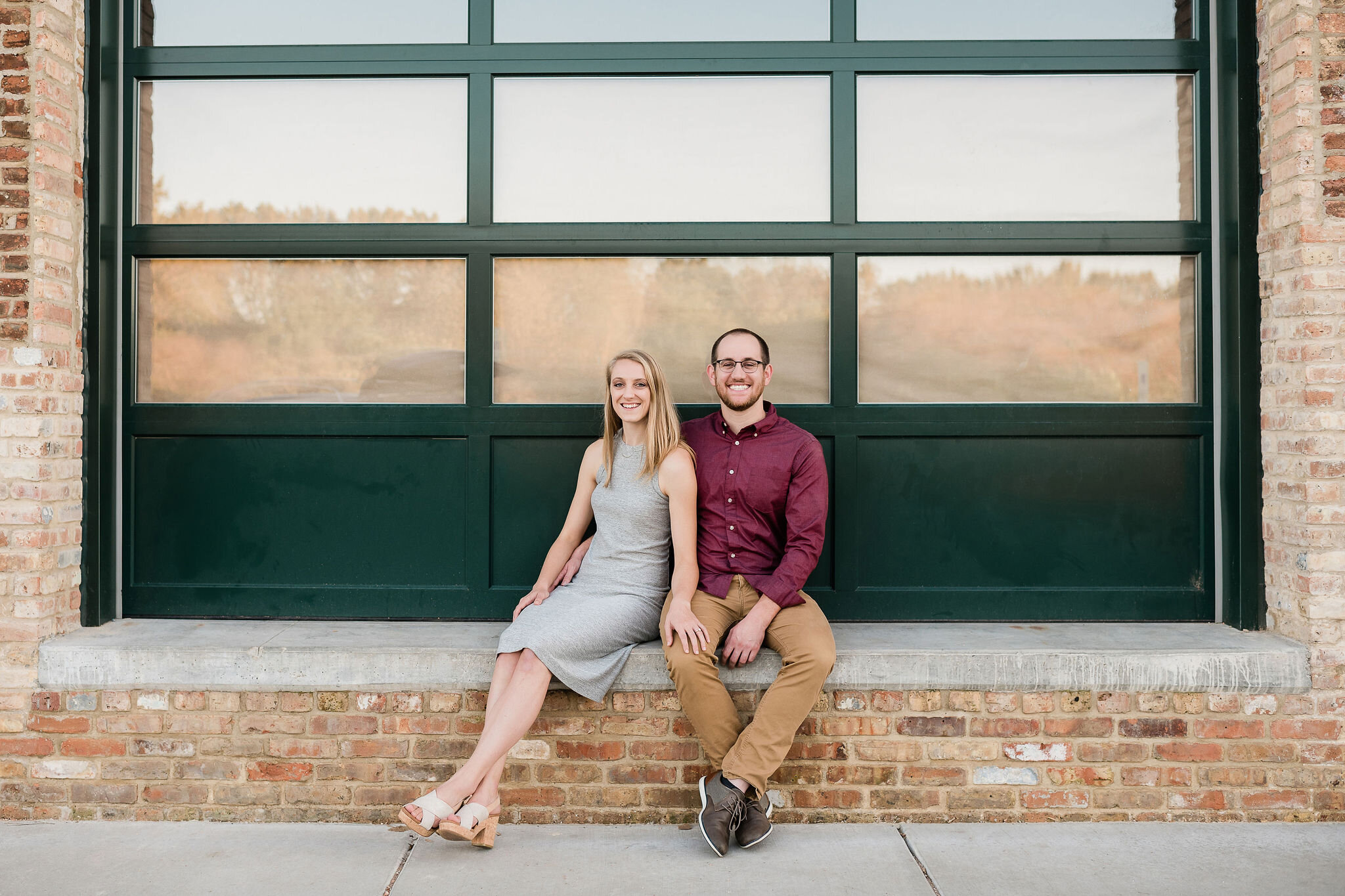 Engaged couple sitting in front of a big window