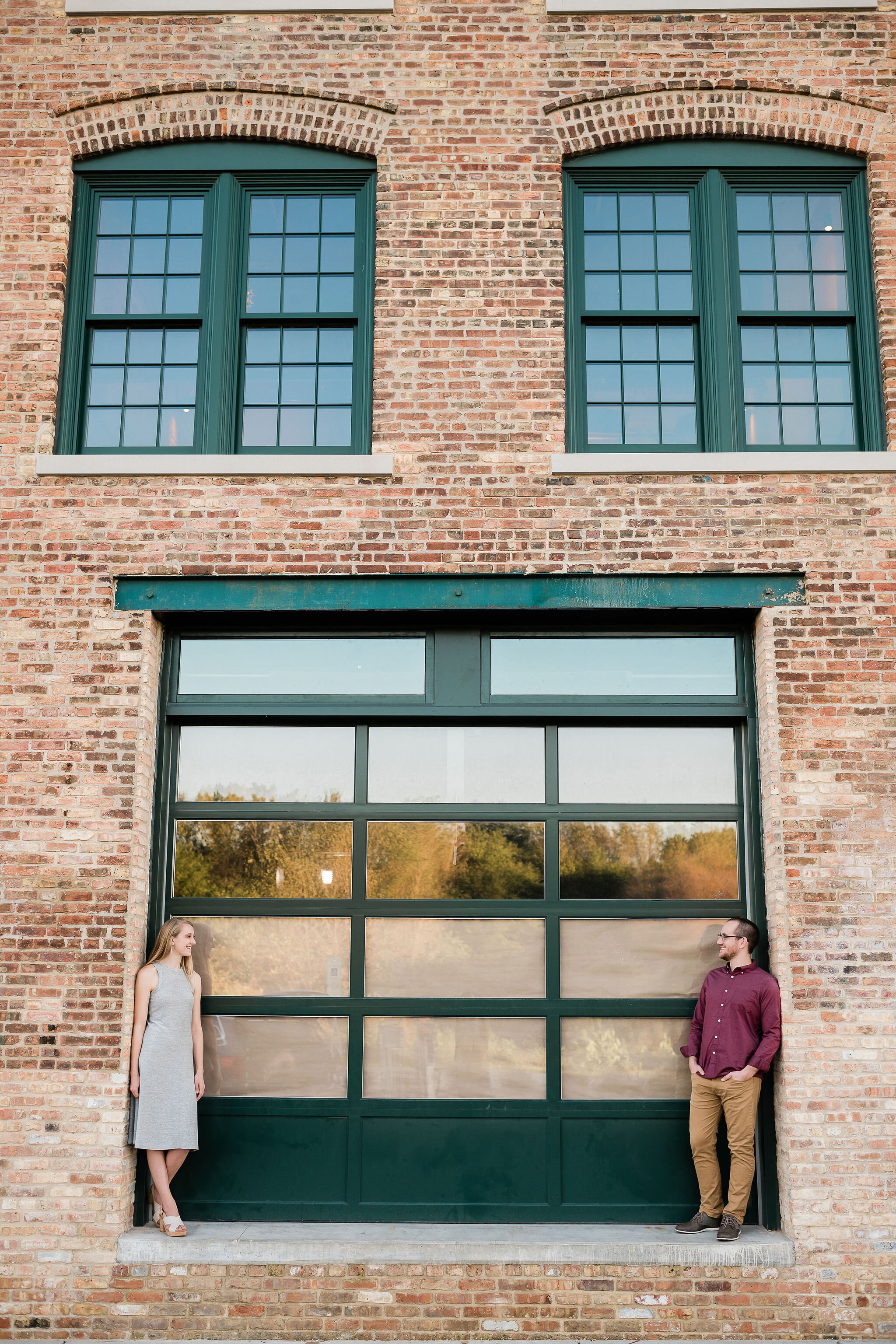 Engaged couple standing in front of a brick building