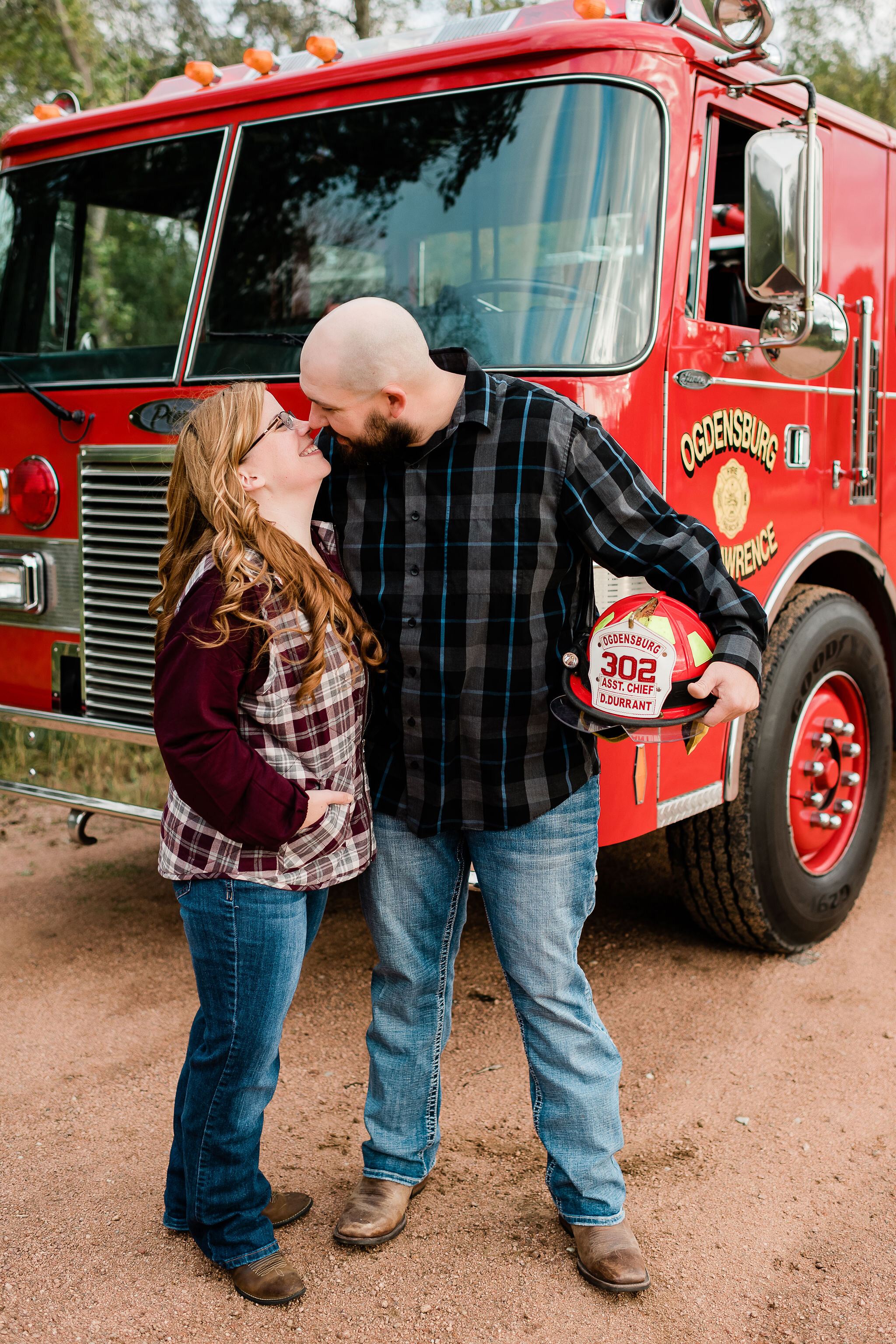 Engaged couple kissing in front of a fire truck