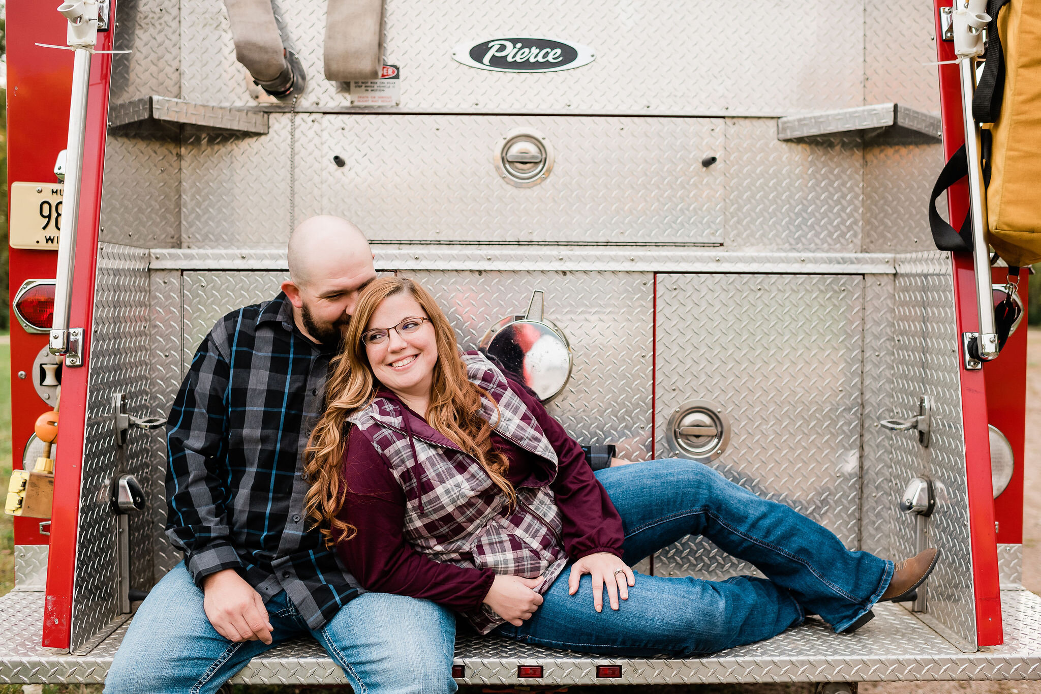 Engaged couple sitting on a fire truck