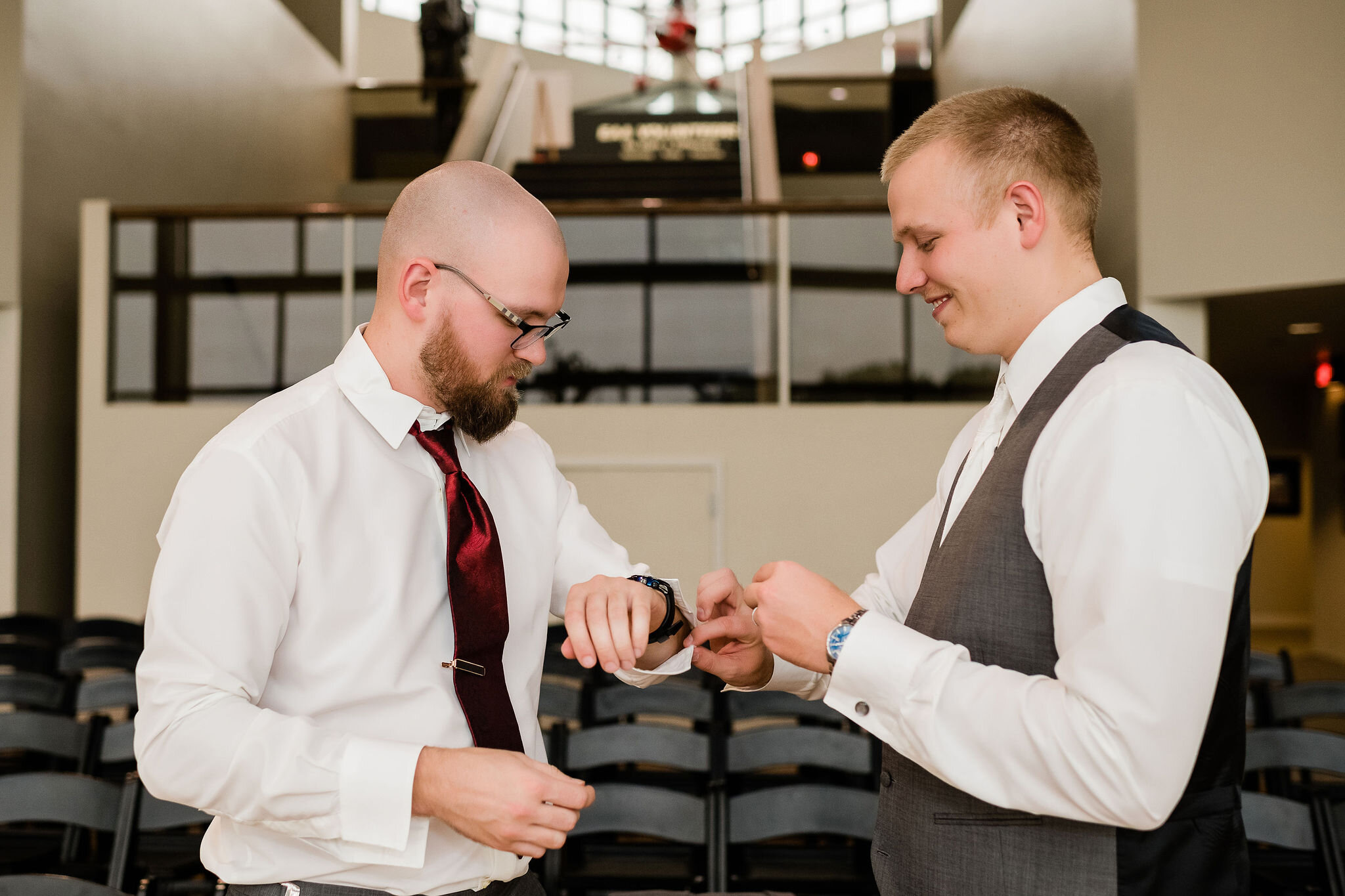 Groomsman helping groom with his cufflinks
