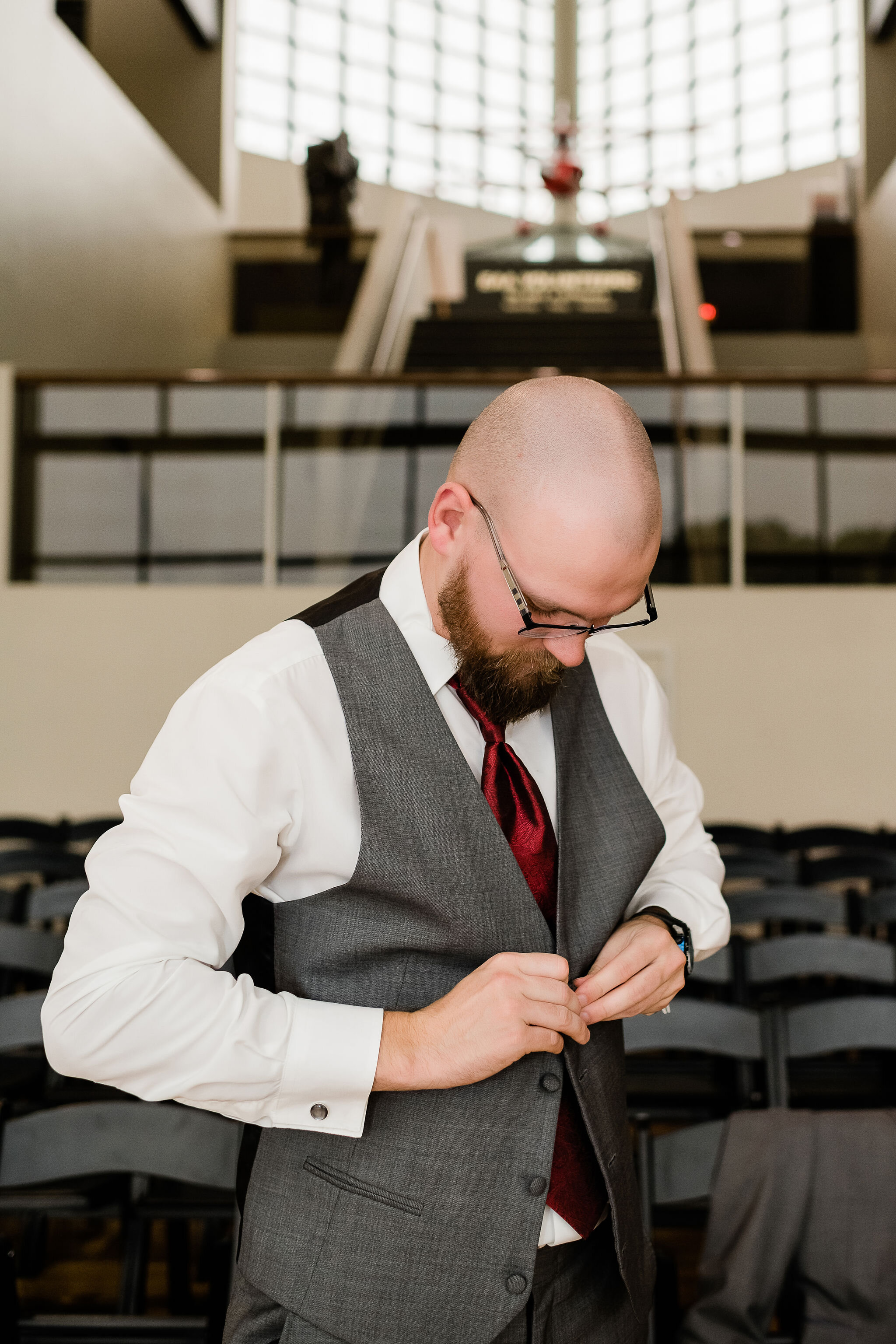 Groom buttoning up his vest
