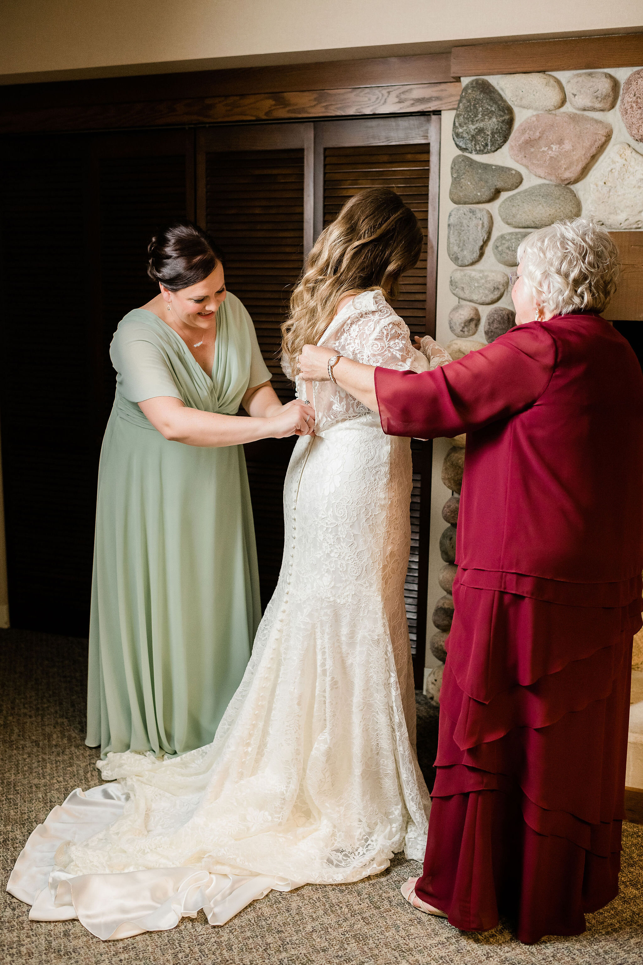 Bride's mom and sister buttoning up her dress