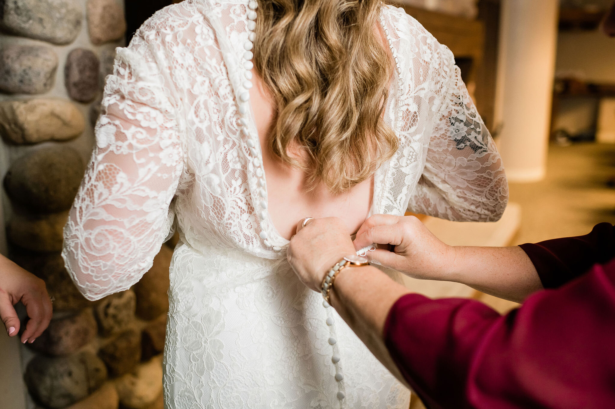 Bride's mom buttoning up bride's dress
