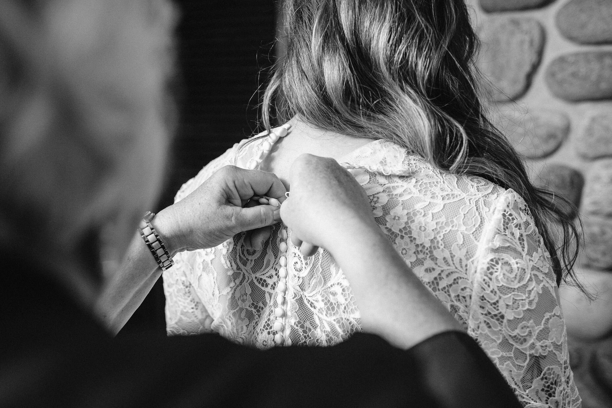 Bride's mom buttoning up bride's dress