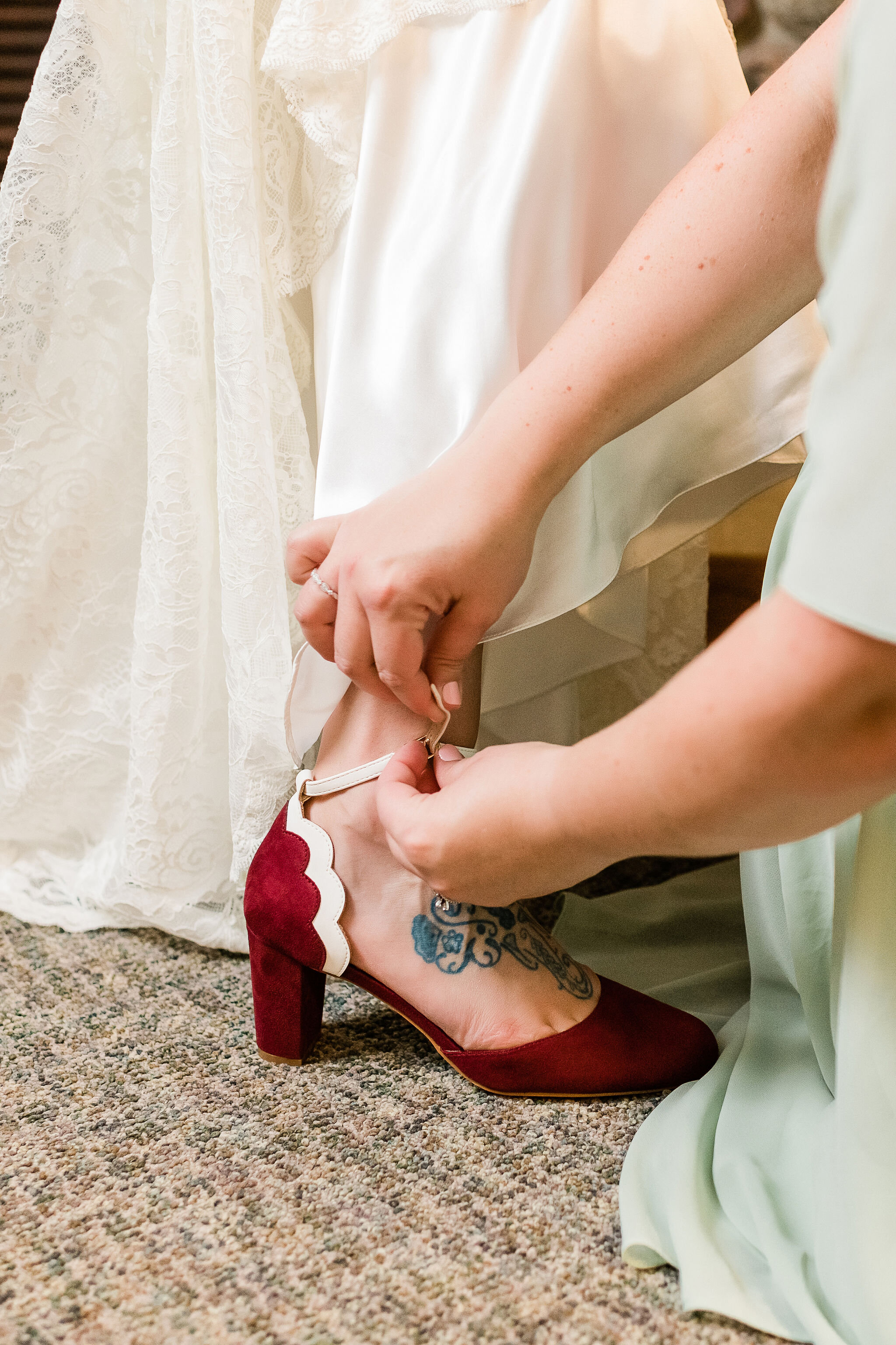 Bride's sister putting bride's shoe on