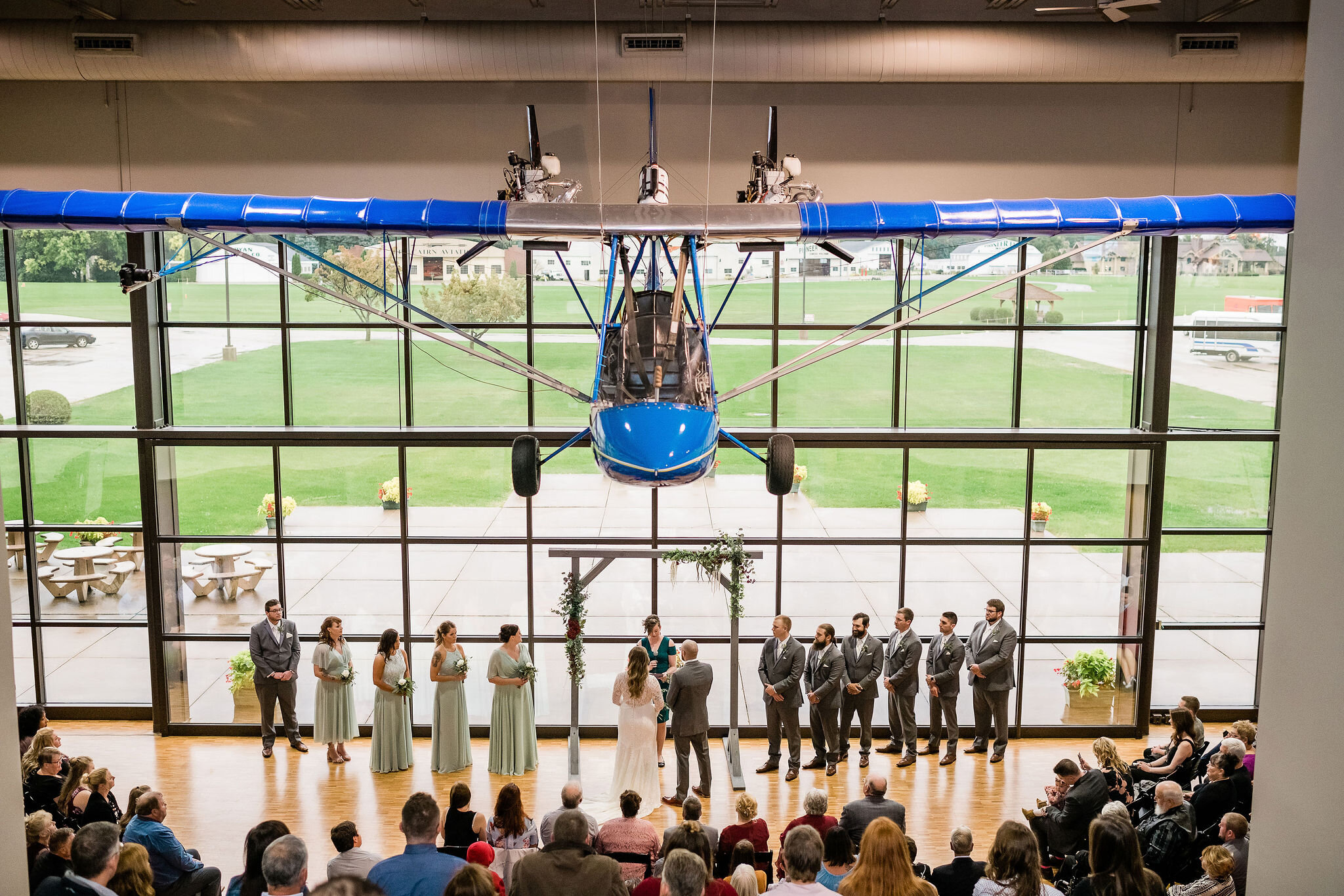 Wide view of wedding ceremony with an airplane hanging from the ceiling
