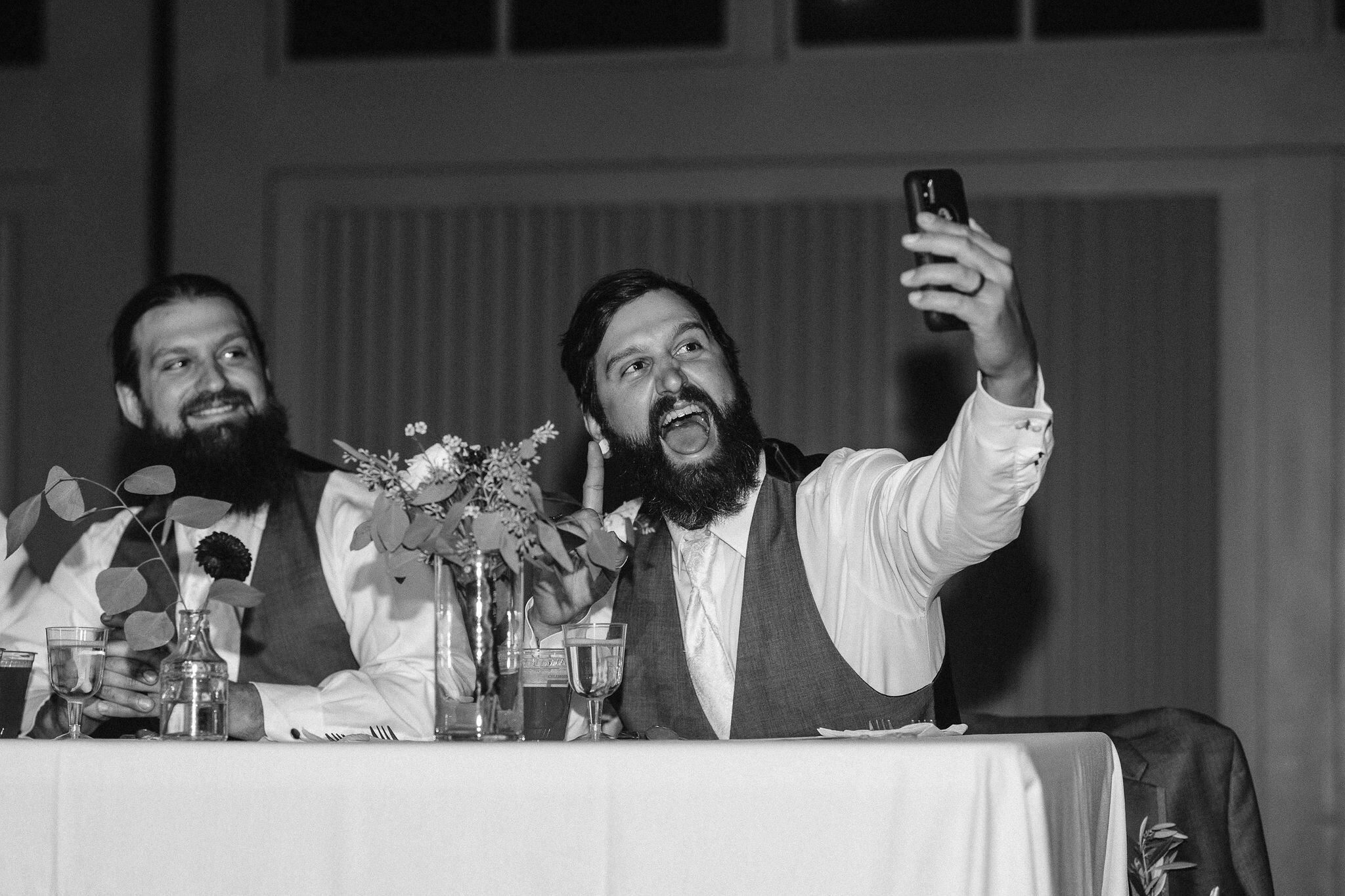 Groomsman taking a selfie at the head table