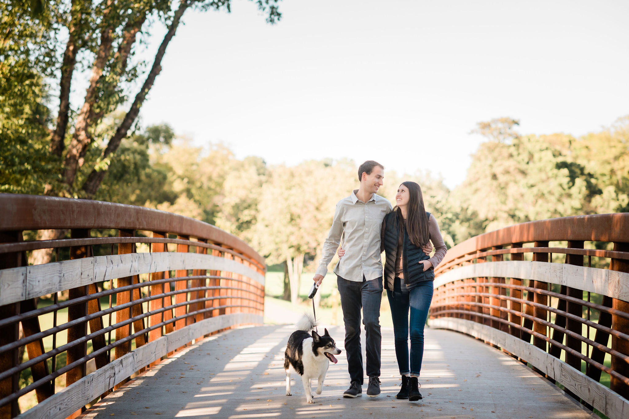 Engaged couple walking on a bridge with their dog