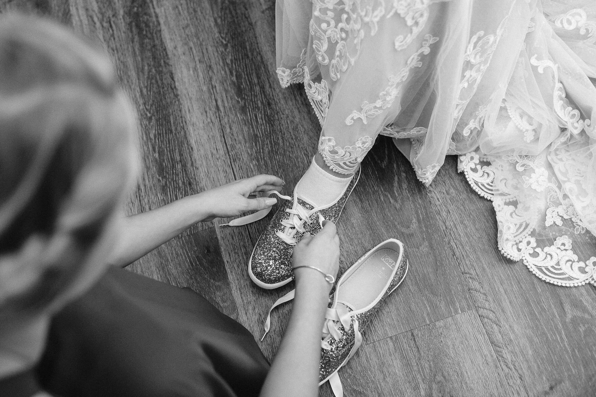 Bridesmaid putting bride's shoes on