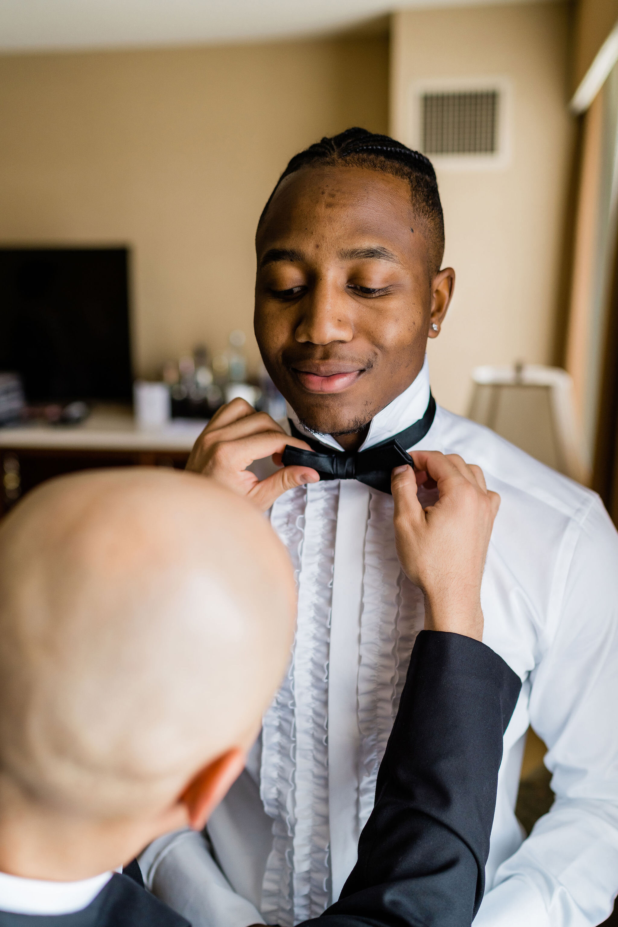 Groom getting his bowtie put on