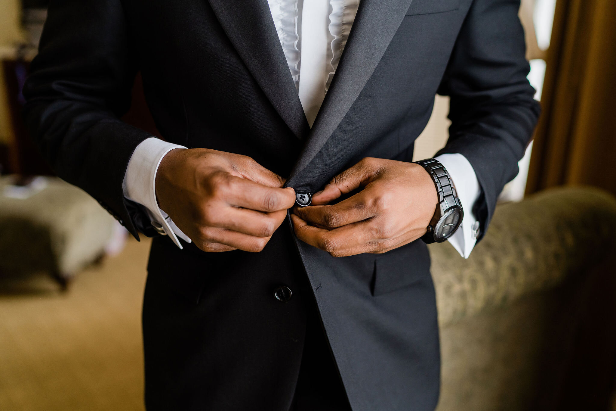 Groom buttoning up his suit jacket