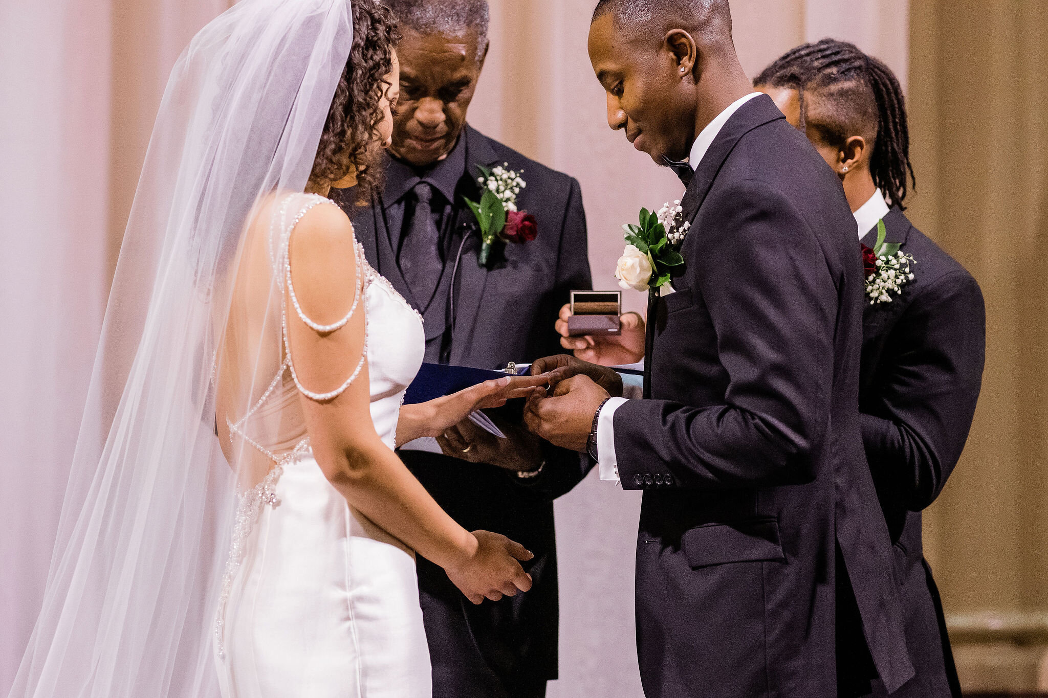 Groom putting ring on bride's finger