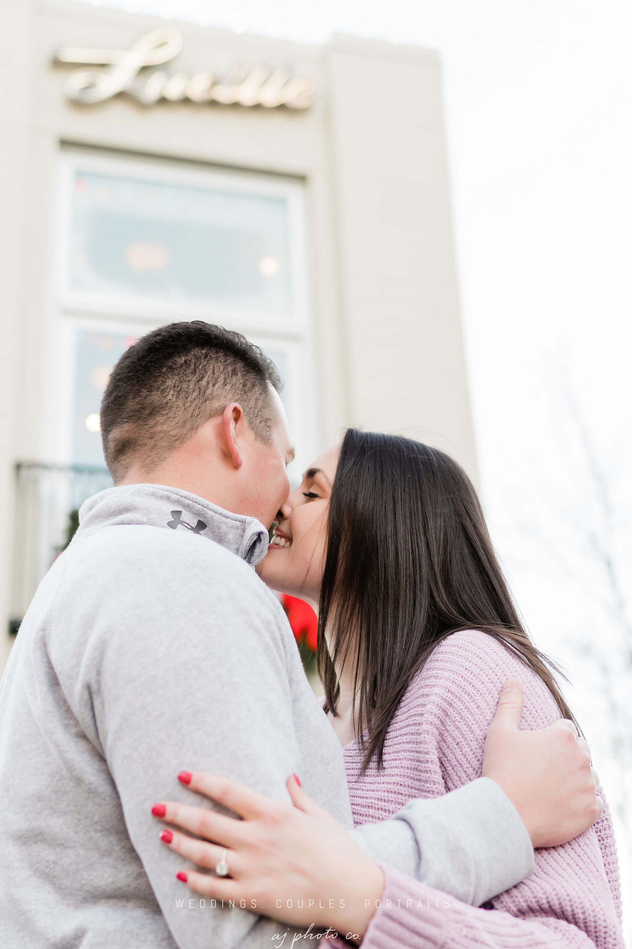 Engaged couple kissing in front of Lucille in Madison, WI