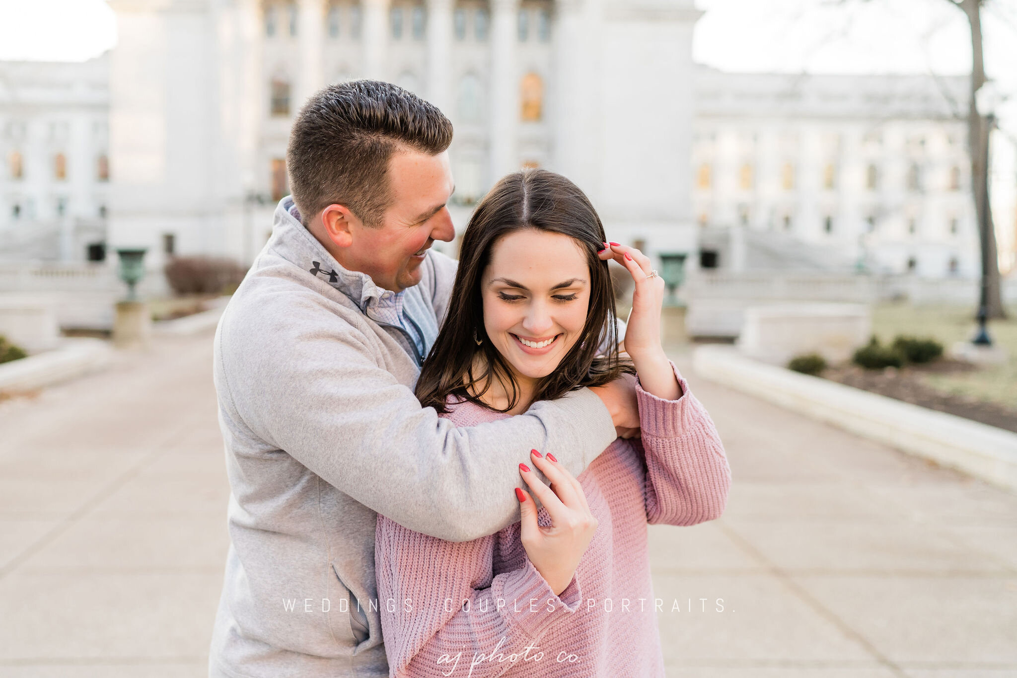 Engaged couple laughing in front of Wisconsin State Capitol