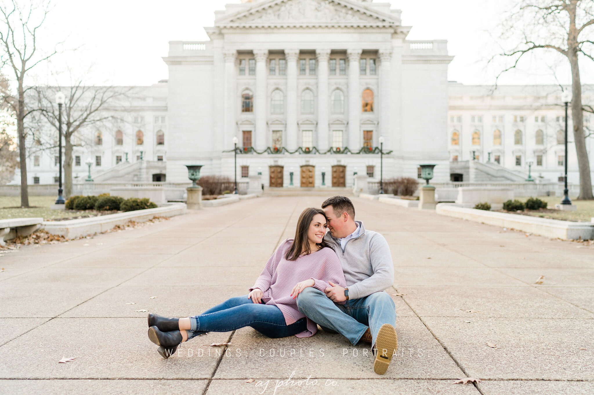 Engaged couple sitting in front of Wisconsin State Capitol