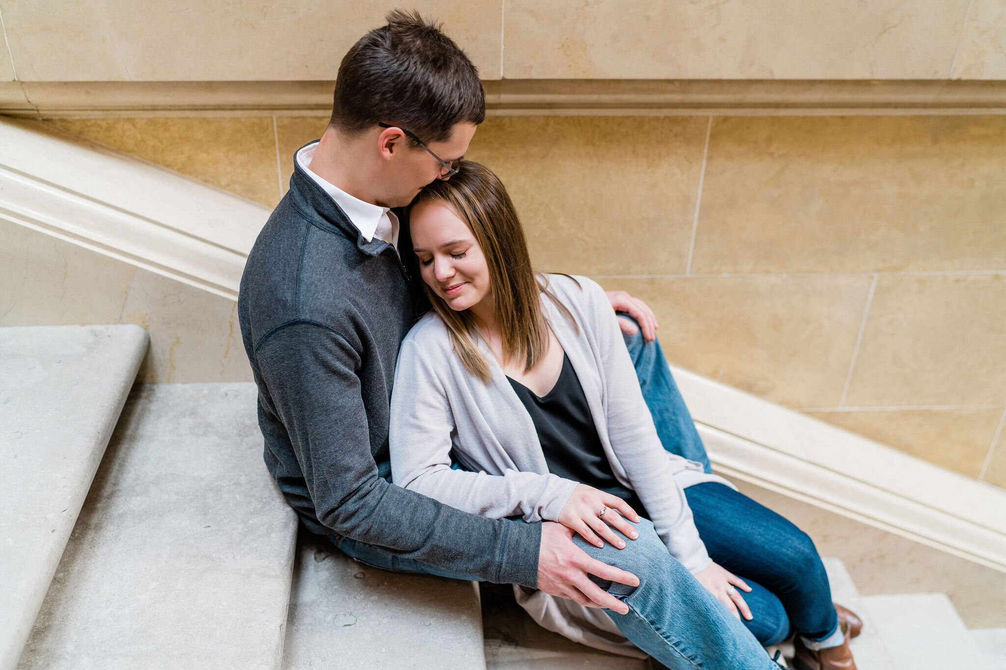 Engaged couple sitting inside Wisconsin State Capitol in Madison, WI