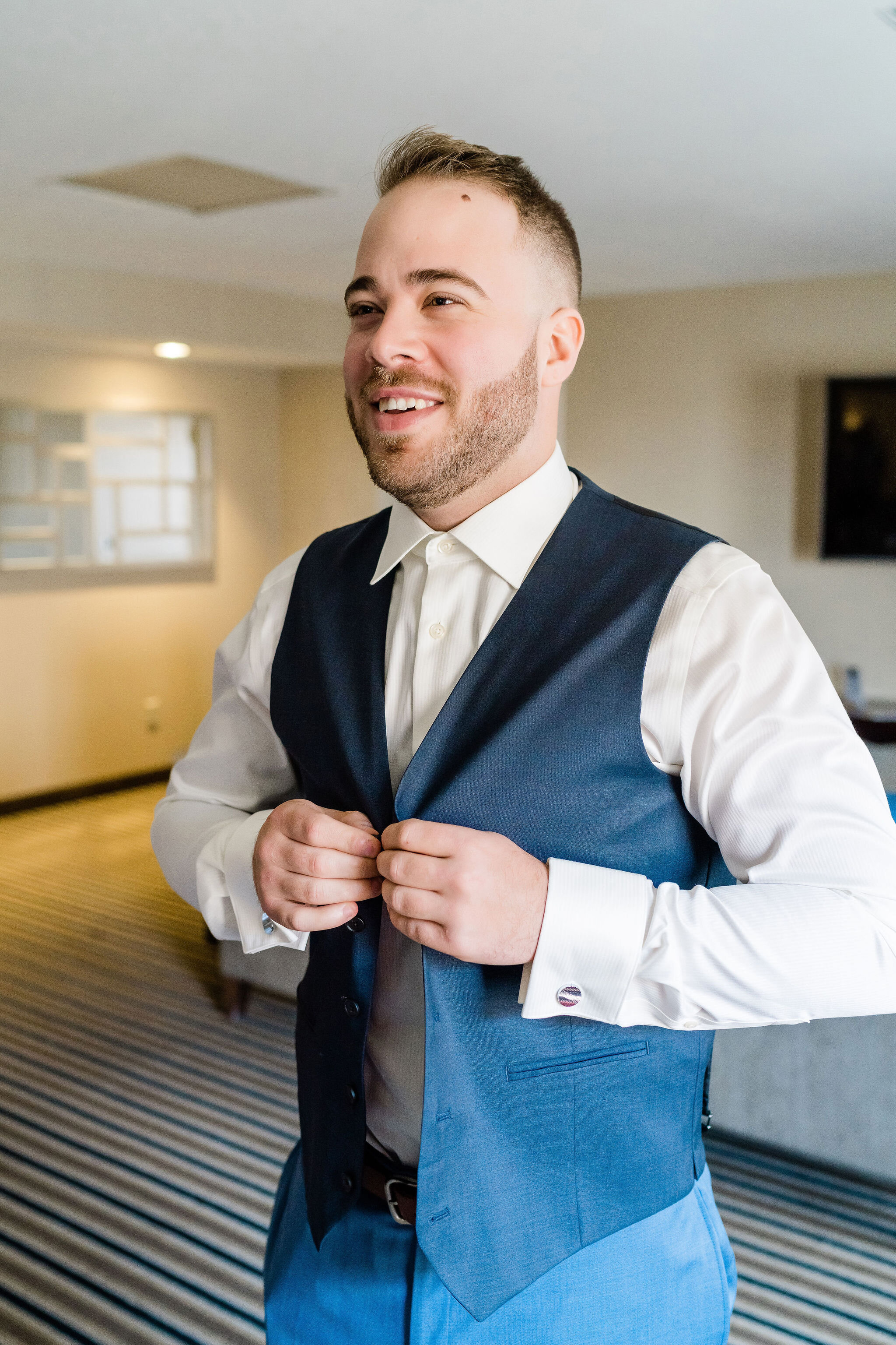 Groom buttoning up his vest