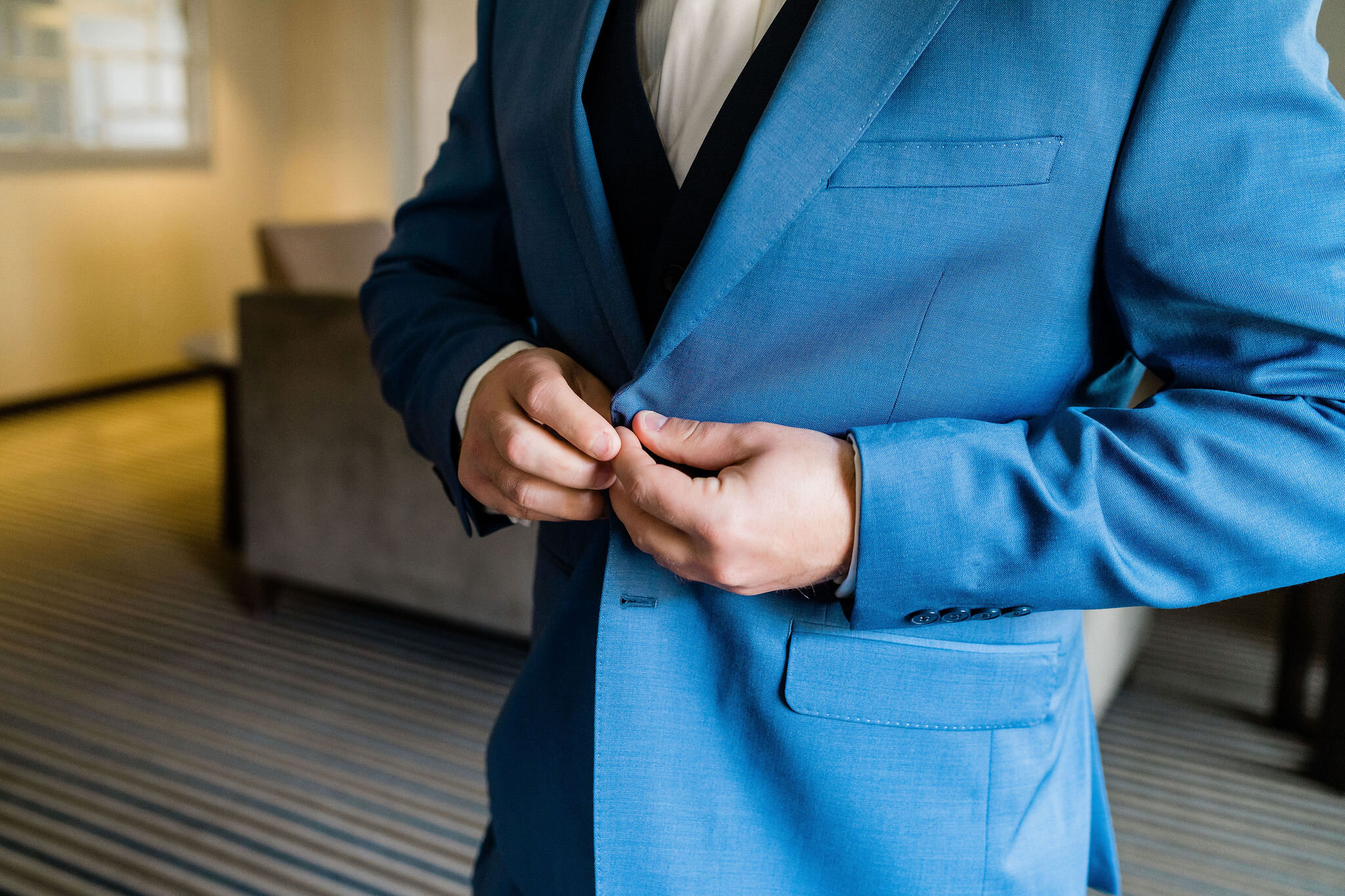 Groom buttoning up his suit jacket