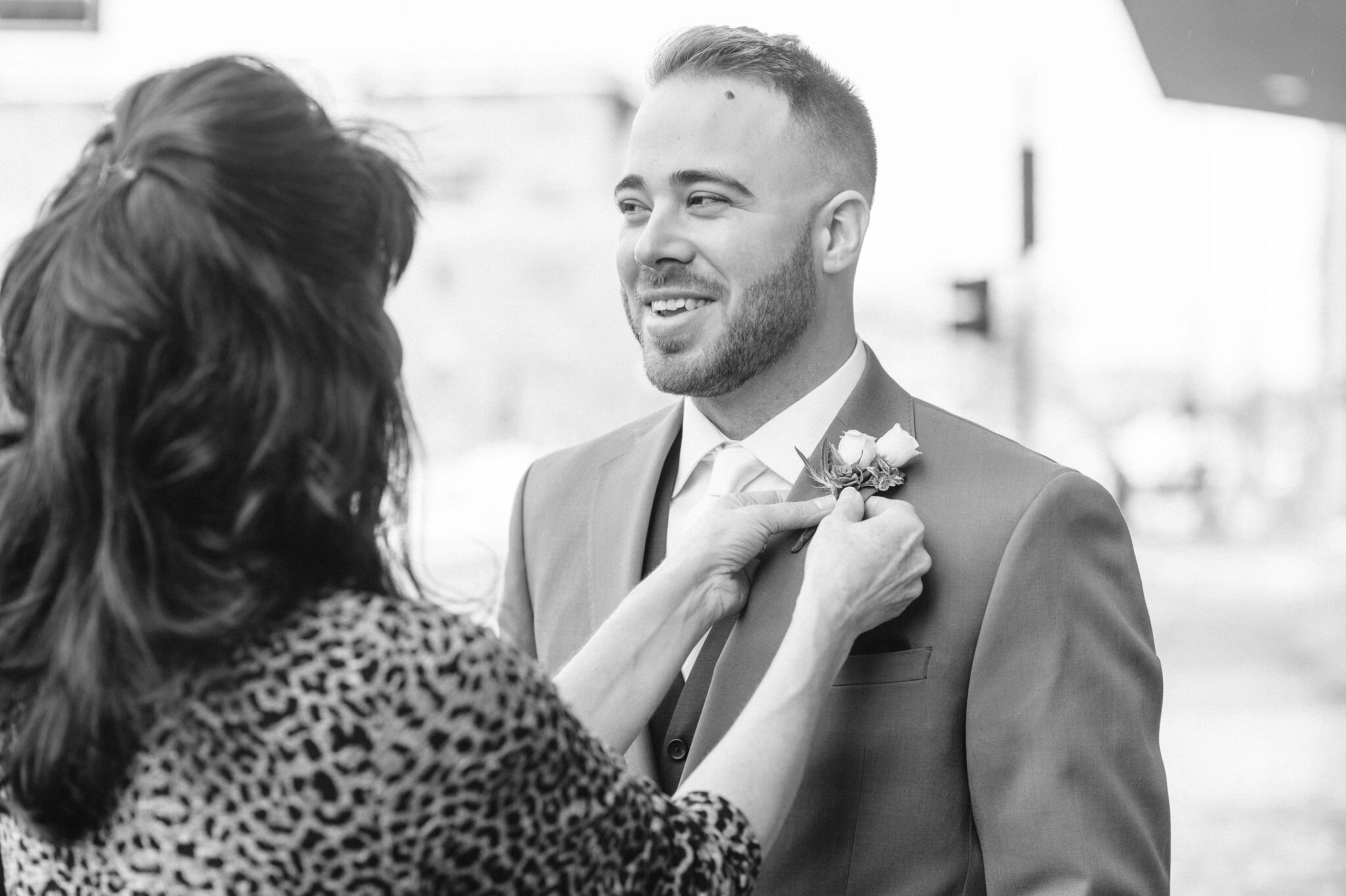Groom getting his boutonniere pinned on