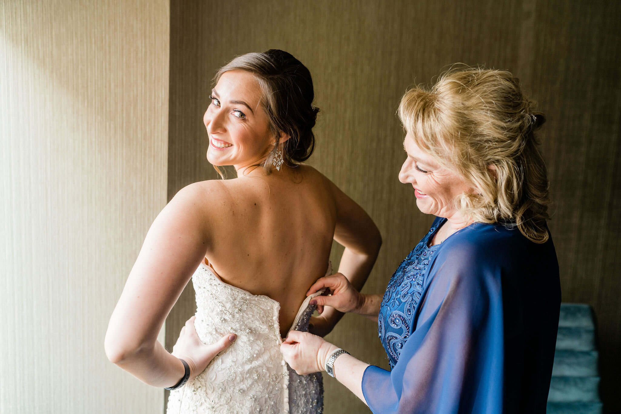 Mother of the bride zipping up bride's dress