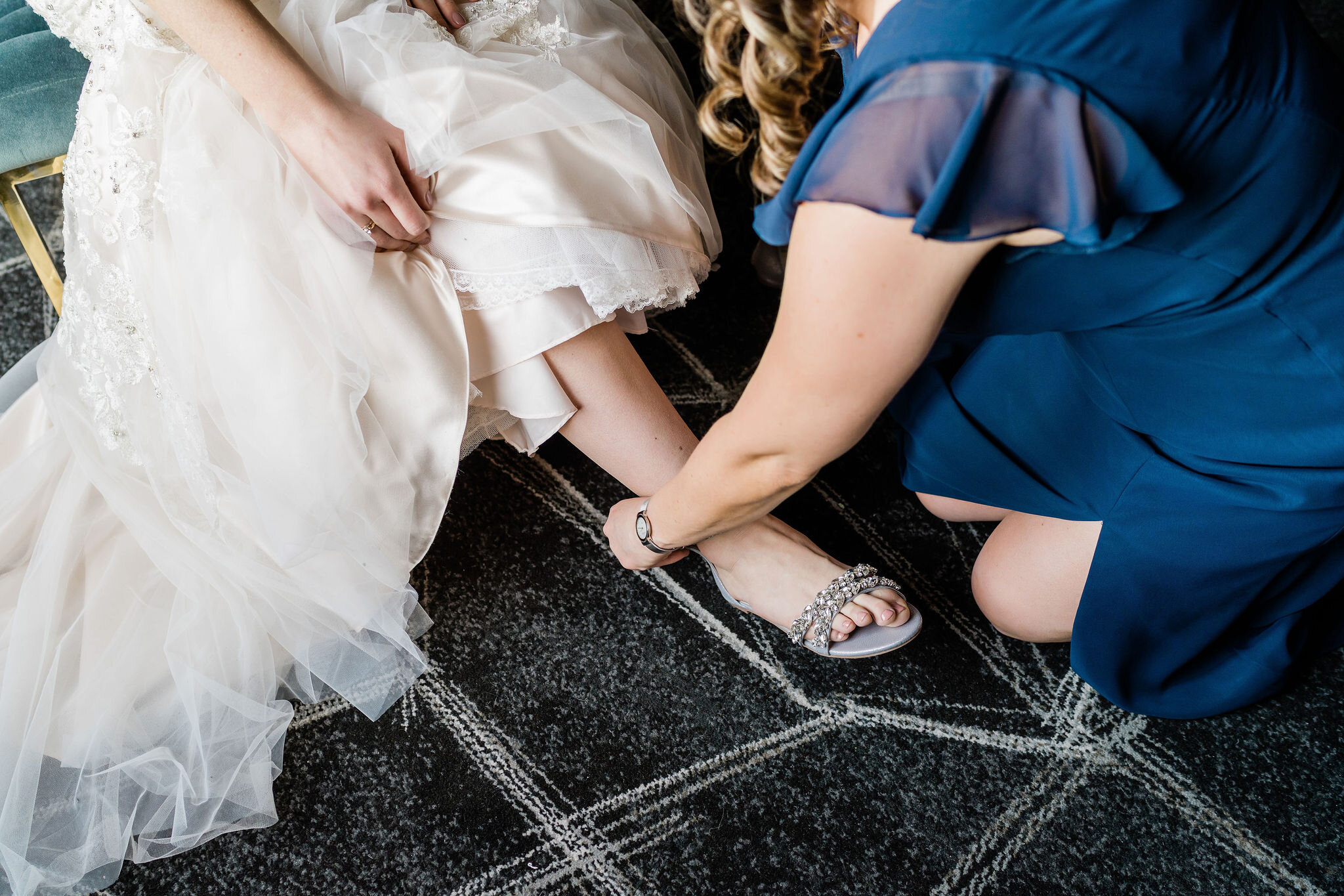 Mother of the bride putting bride's shoes on her