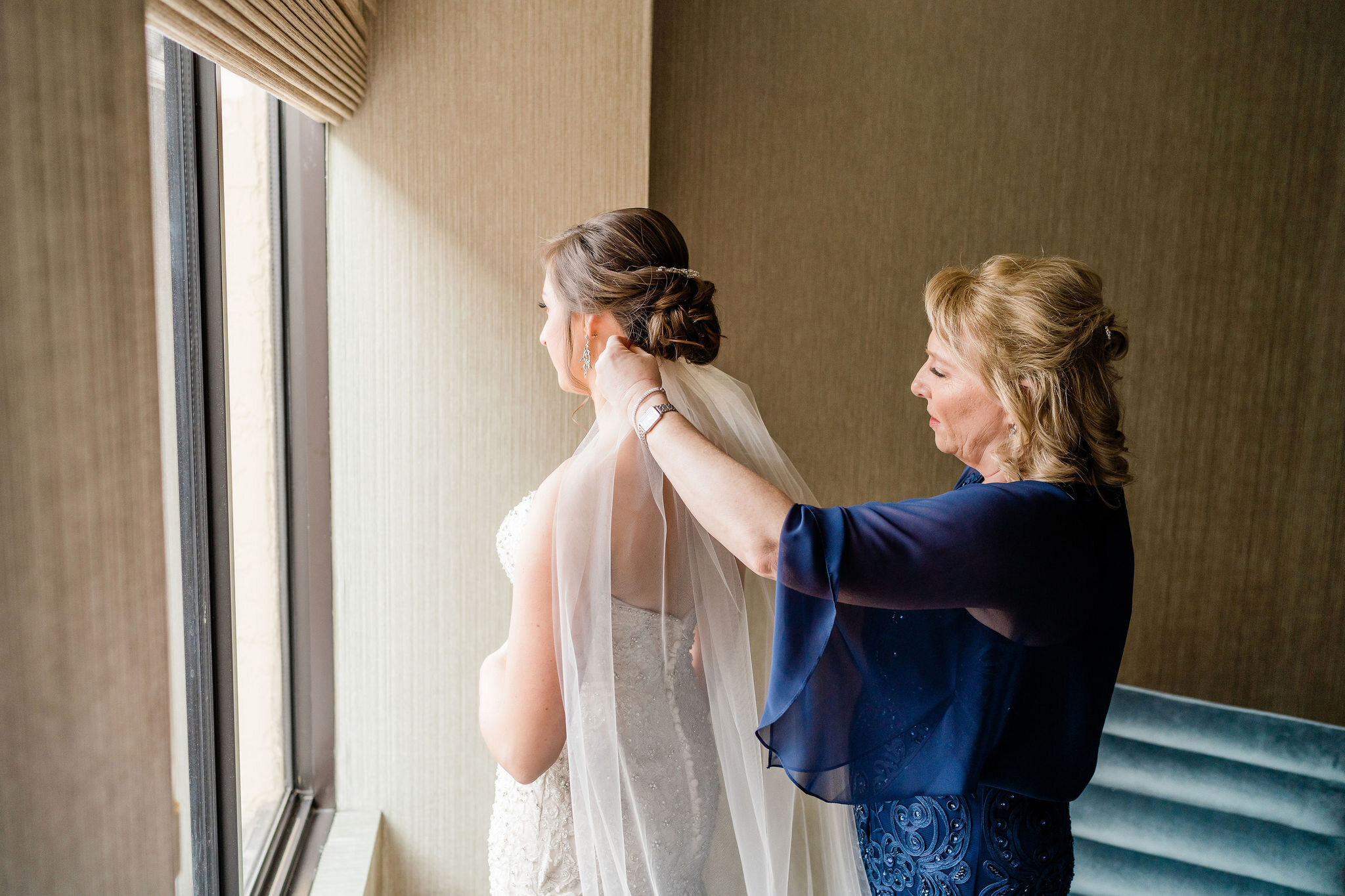 Mother of the bride putting the bride's veil on her