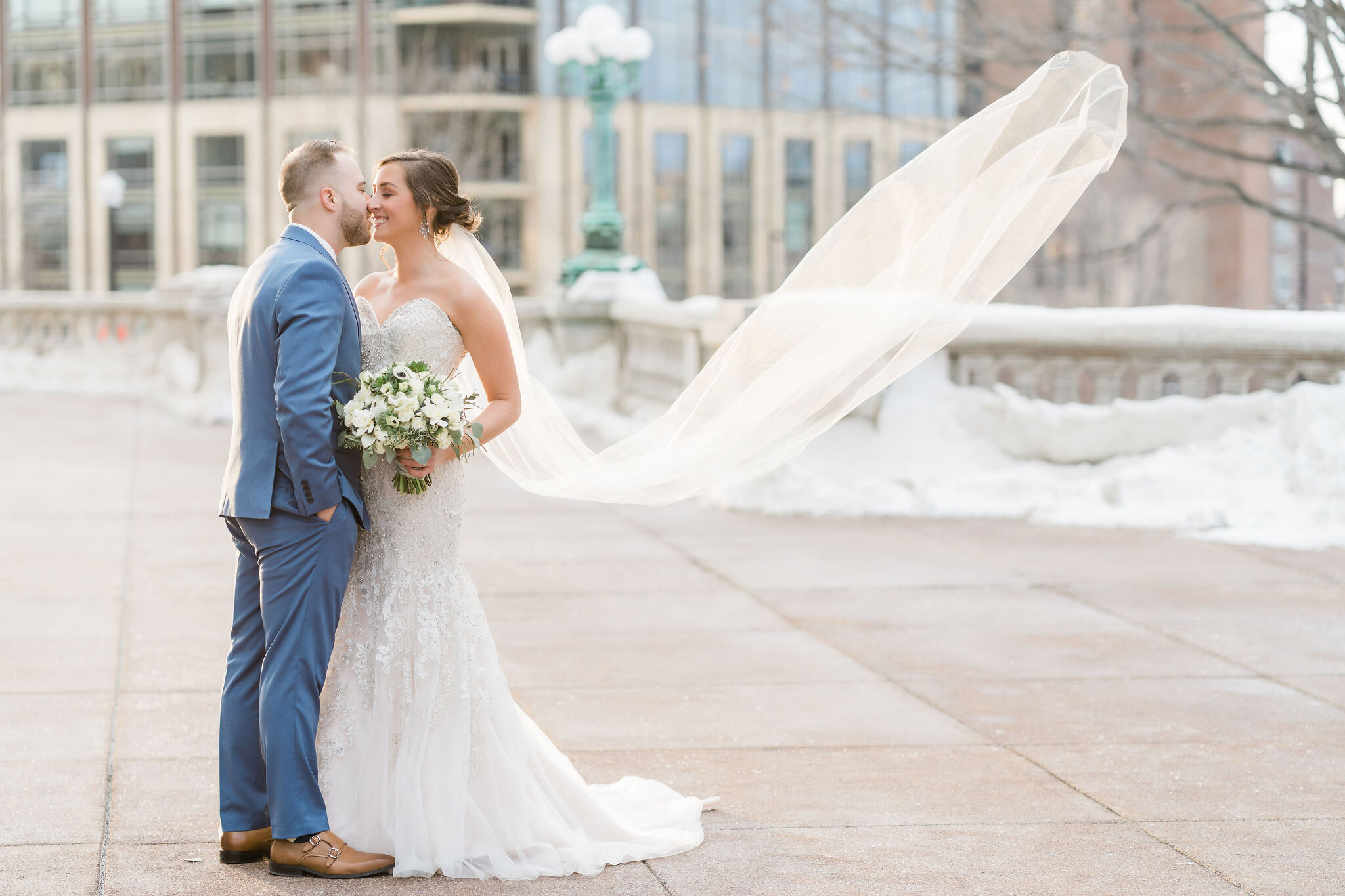 Bride and groom with bride's veil blowing in the wind