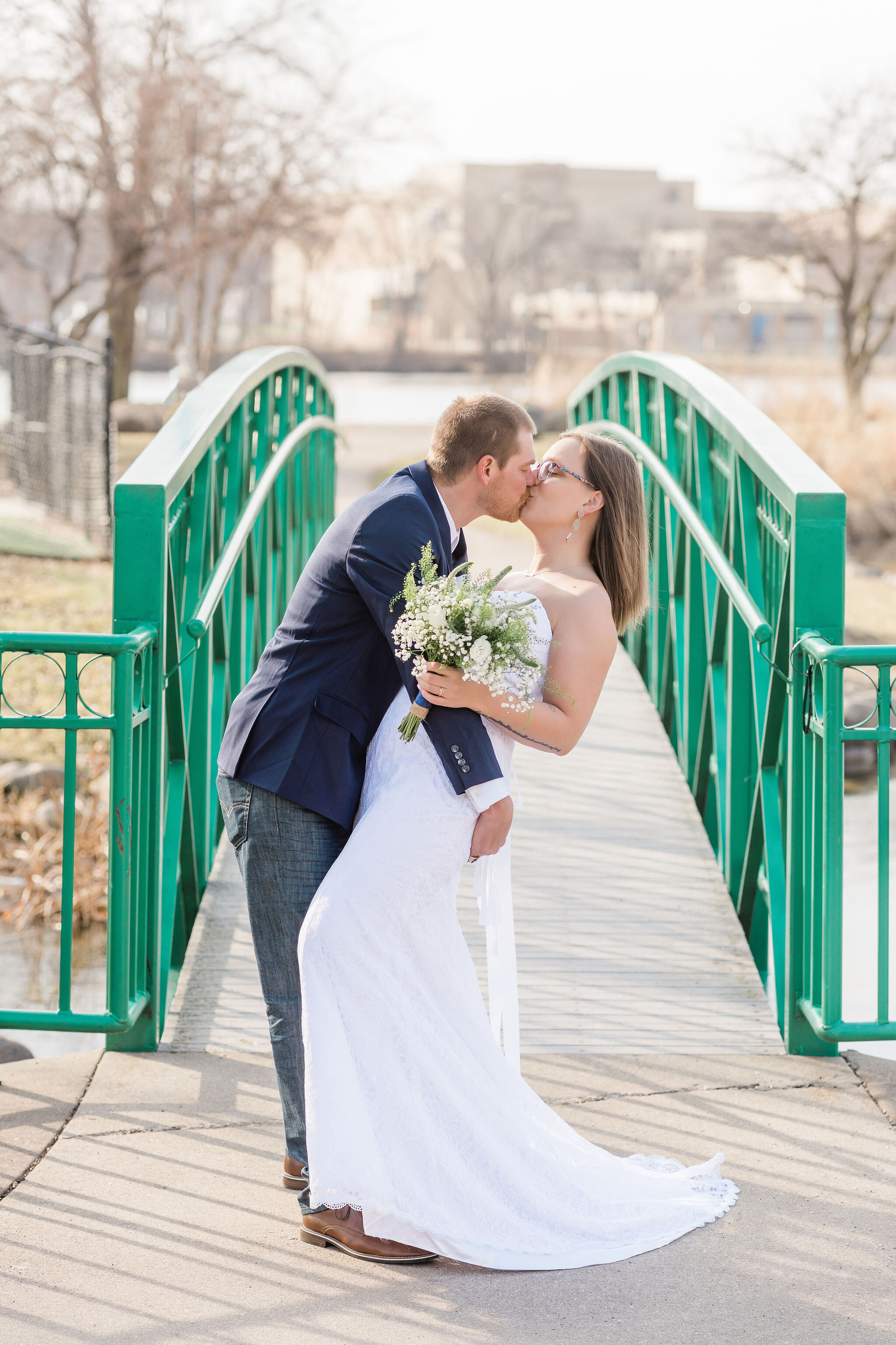 Bride and groom kissing in front of a bridge
