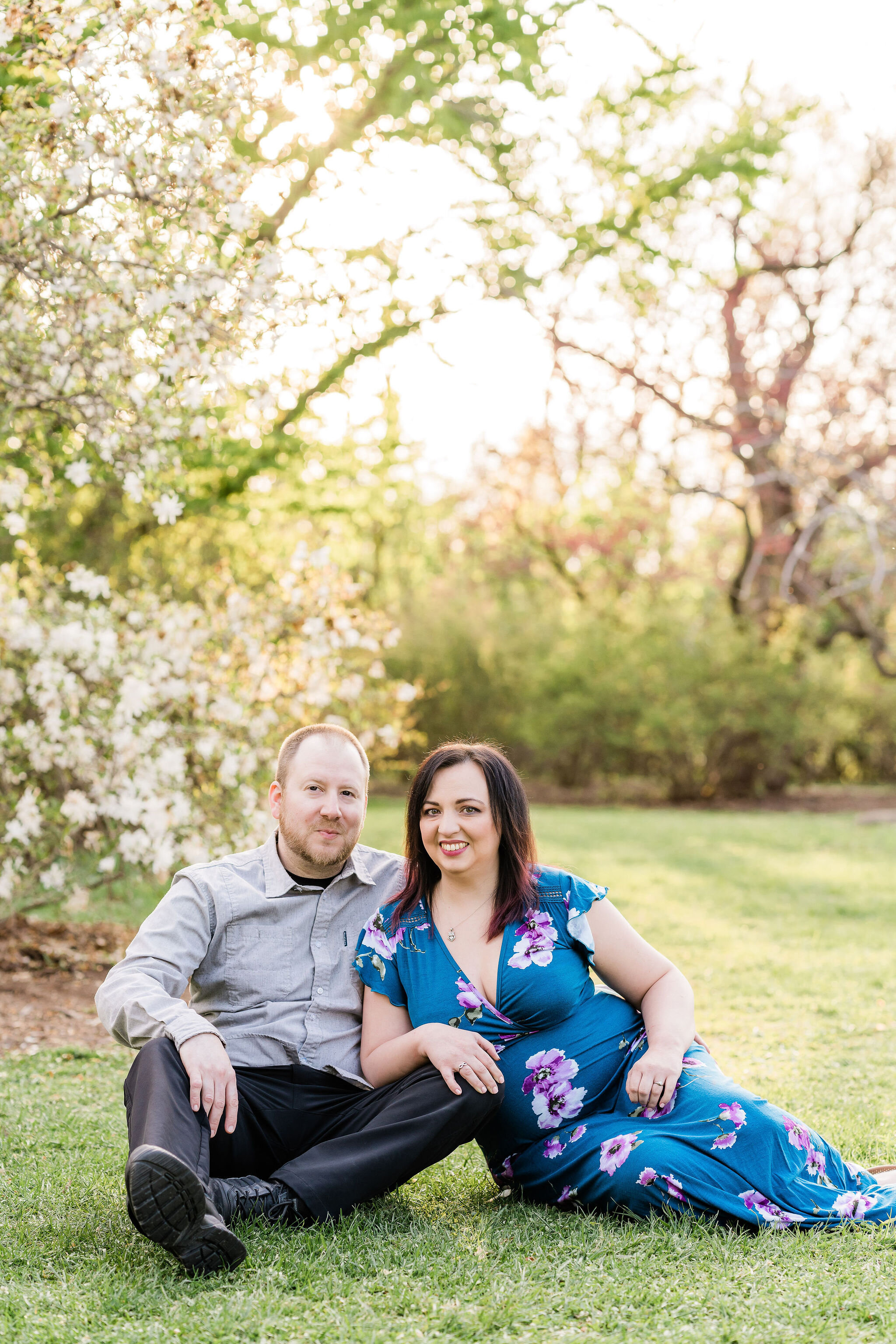 Engaged couple sitting by a magnolia tree