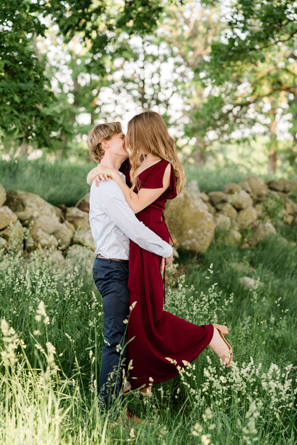 Man kissing his fiancé as he lifts her up