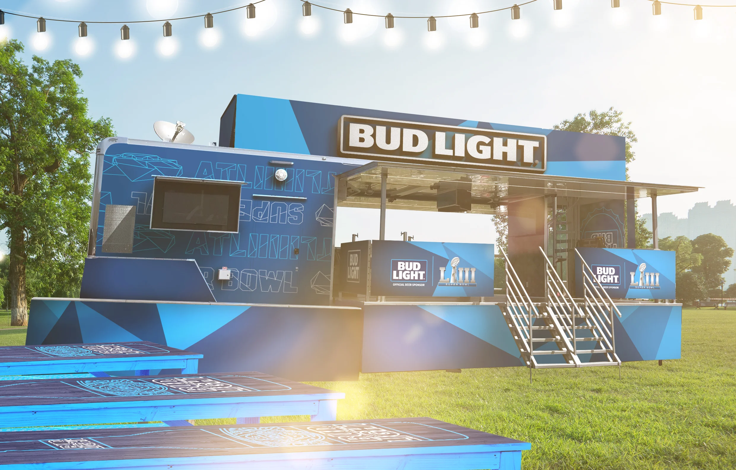 Stage set up for Super Bowl LIV, sponsored by Bud Light, outdoors in a park with trees and string lights, featuring stairs leading up to the stage.