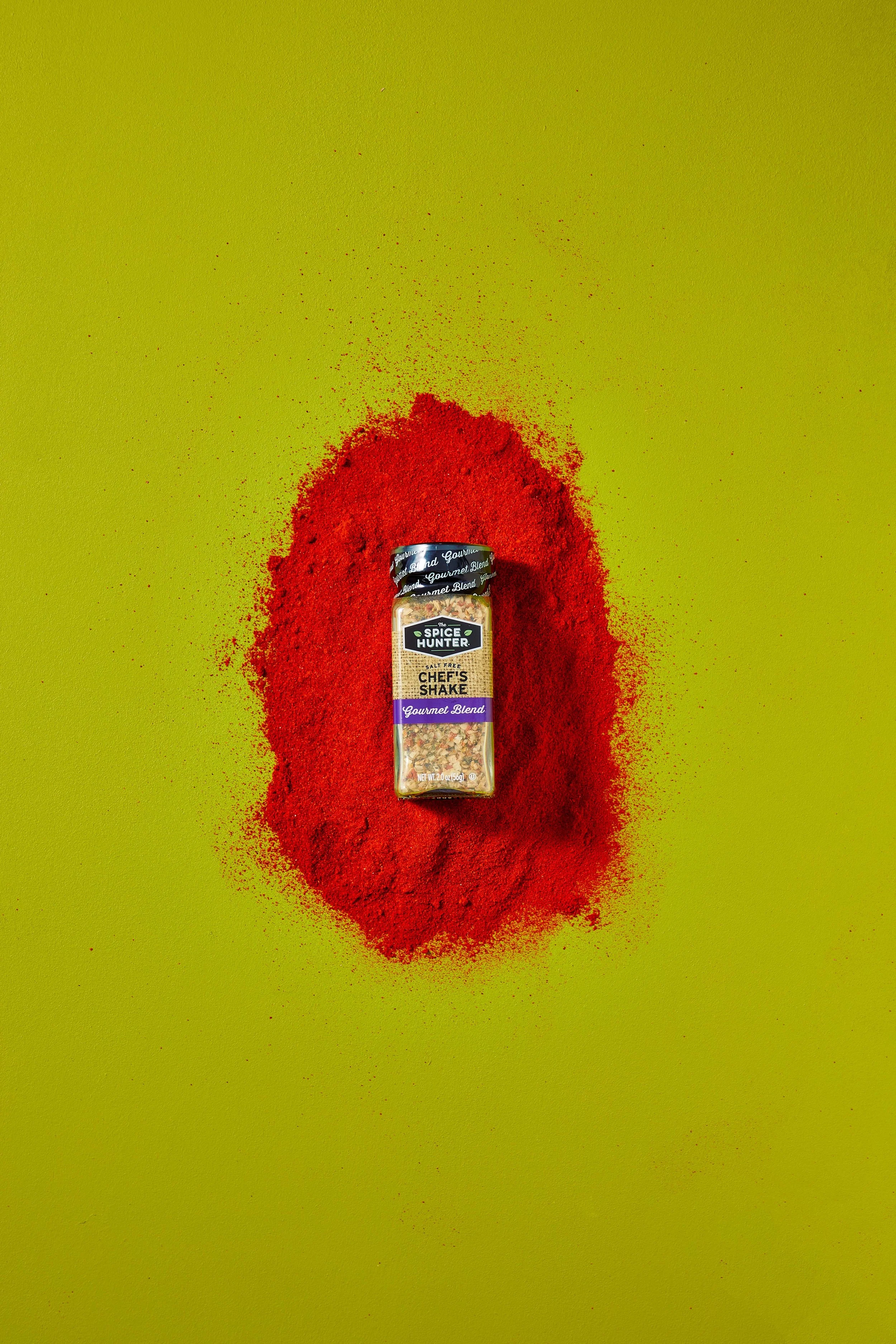 A spice jar labeled 'Gourmet Blend' surrounded by red paprika spice on a bright green background.