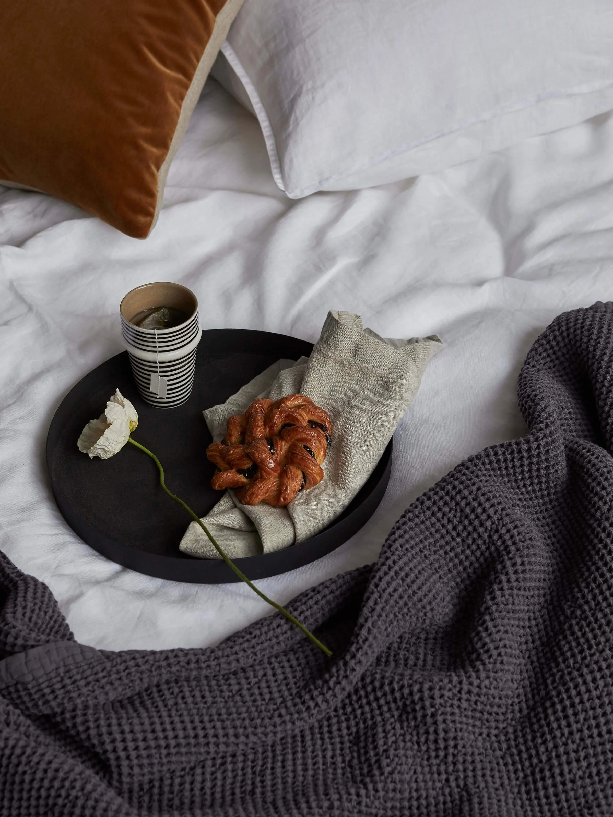 black tray with pastry and flower on a bed