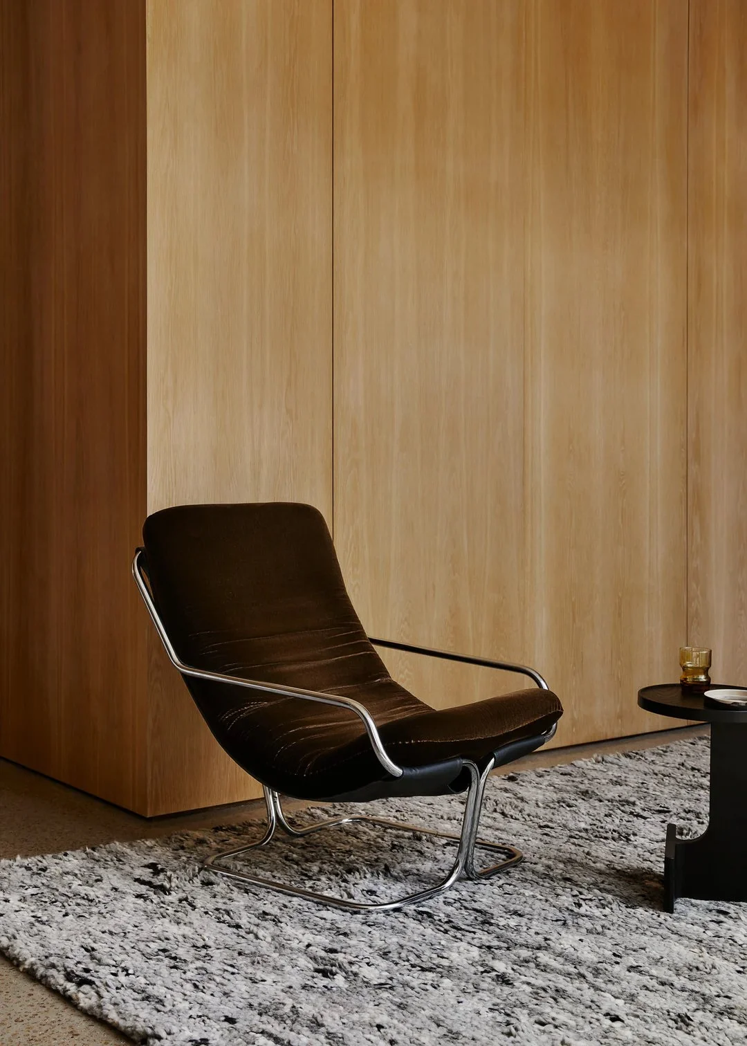 a brown velvet chair on a textured shaggy grey rug