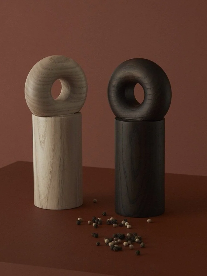 designer timber salt and pepper grinder with spilled pepper on burgundy background