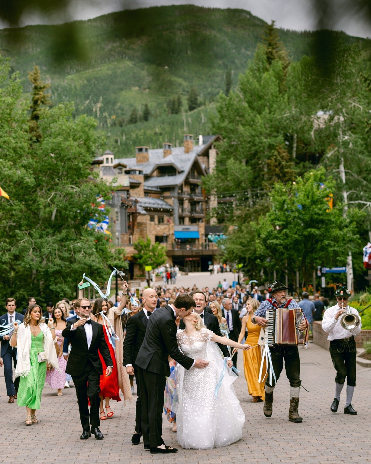 After the ceremony, the wedding party and guests paraded through the streets of Vail, with Bavarian musicians leading the way. The celebration was already in full swing by the time they boarded the gondola to the reception at The 10th. 🎶🏔️🤍