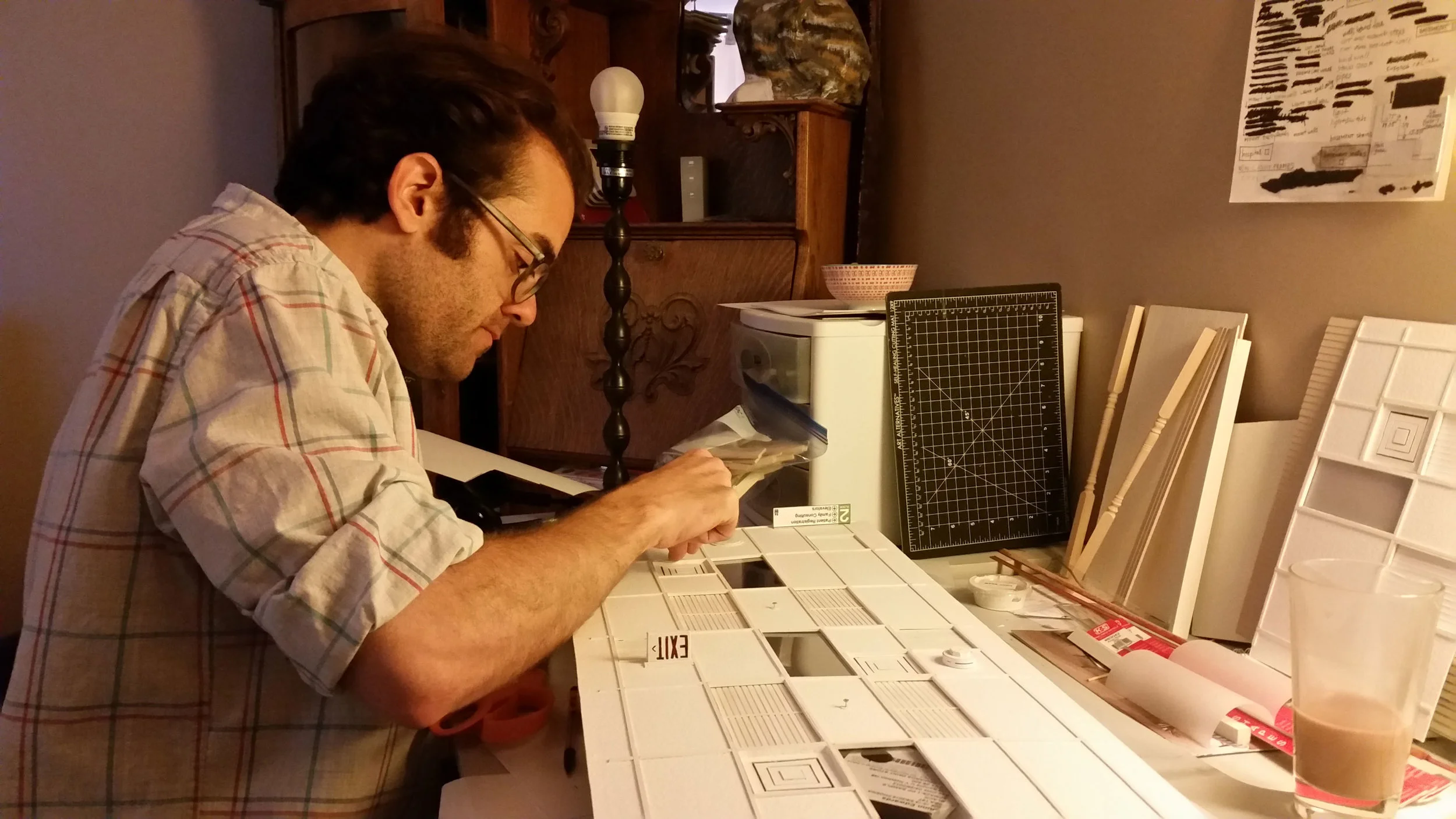 Director Sean David Christensen pieces together ceiling tiles made from watercolor paper for the miniature hospital set.