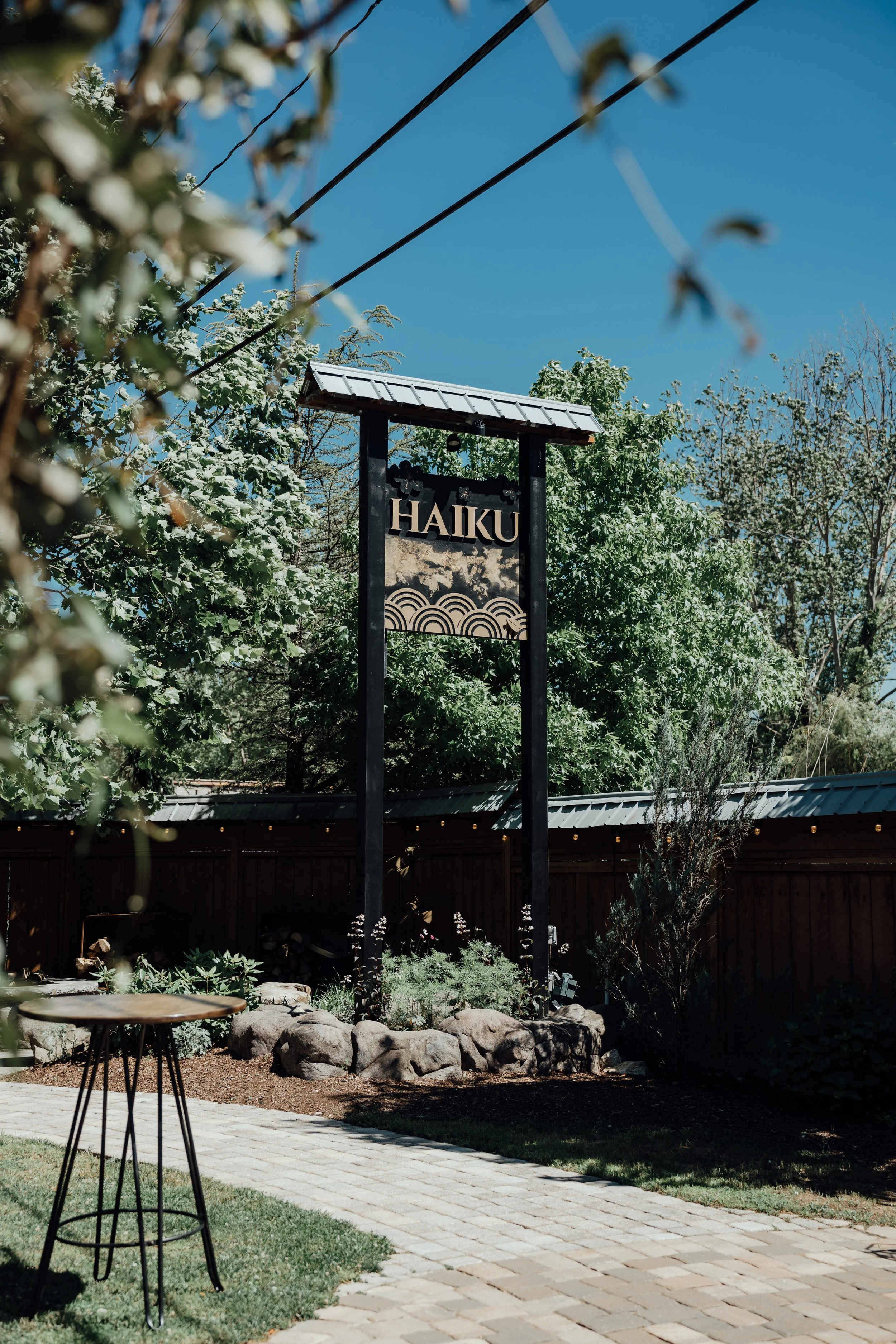 Asheville Wedding Venue Haiku featuring a landscaped garden, stone pathway, lush greenery, and signature Haiku entrance sign in Biltmore Village.