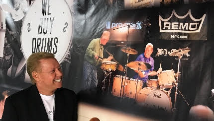Les checks out a show banner with a photo jamming along side fellow drummer Steve Maxwell.