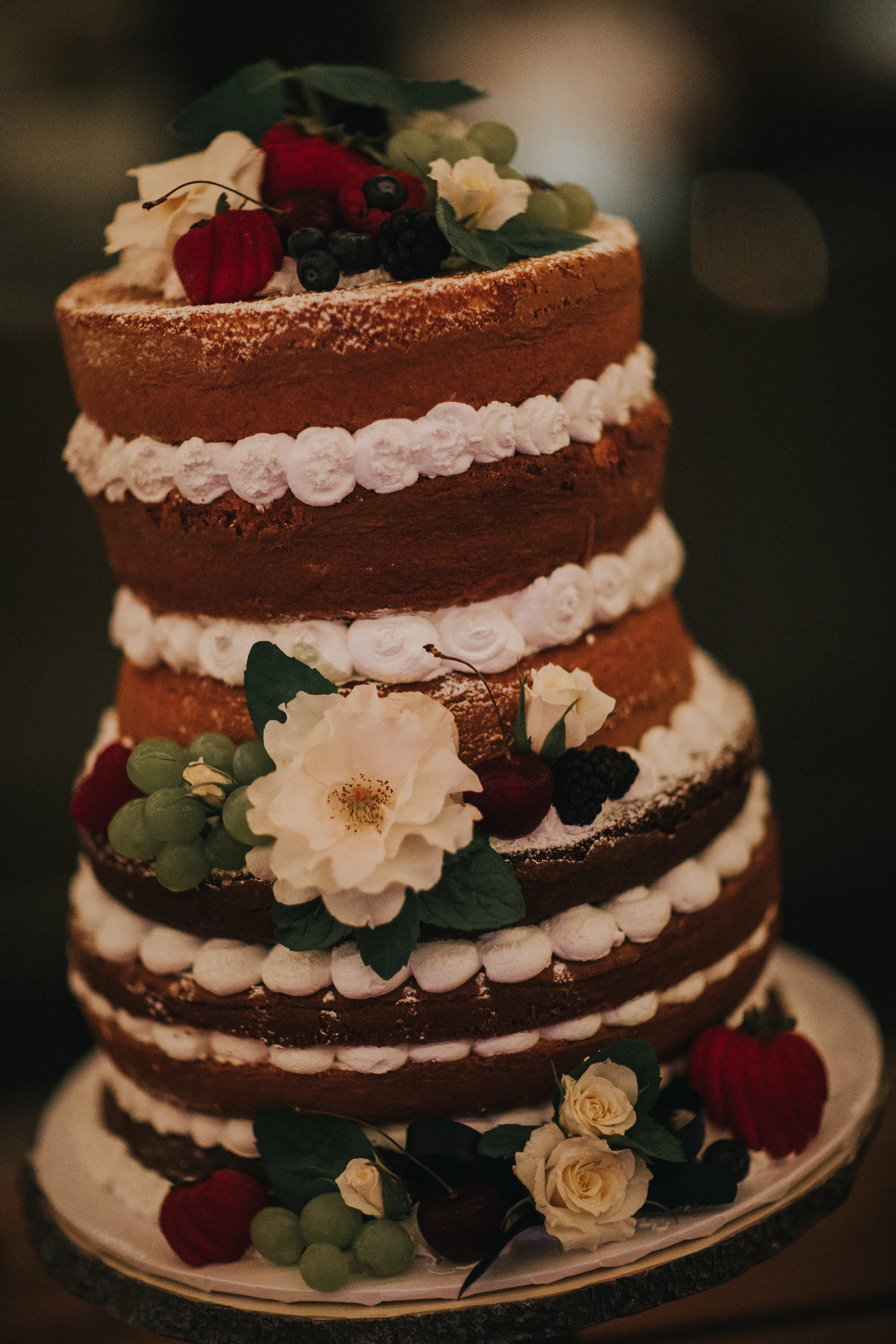 Naked wedding cake topped with fresh fruit and flowers made by a local vendor in the Temecula valley.