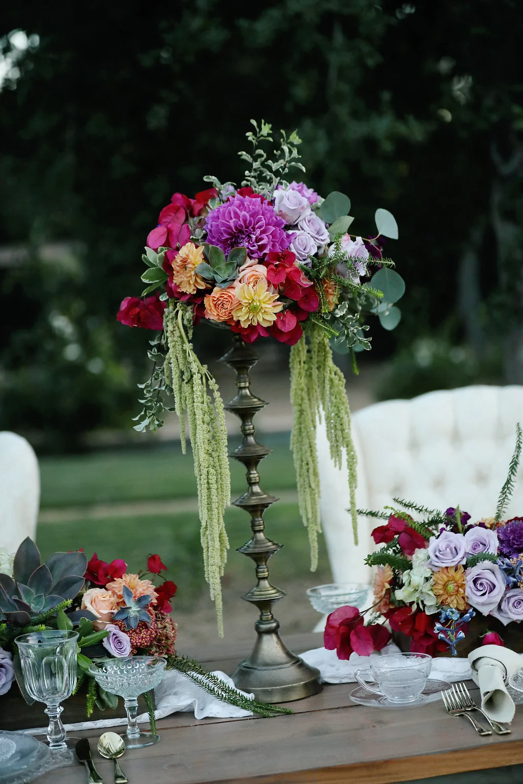 Floral centerpiece sitting on top of a tall brass candle stick on the wedding table at Chateau Adare in the Temecula Valley.