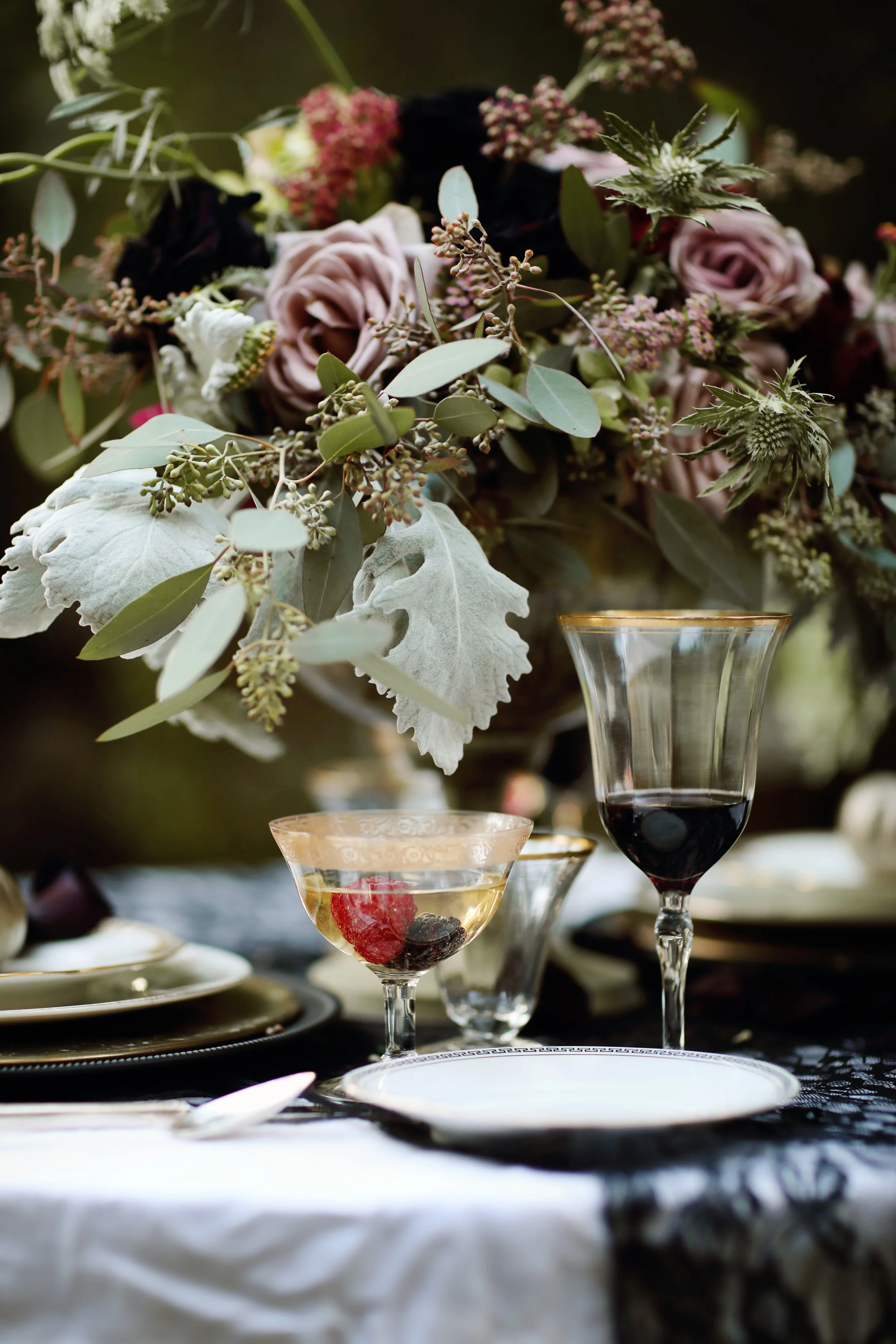 Black Dahlia centerpiece at a wedding table. Gold rimmed goblets and gold china table settings from Birdie in a Barn.