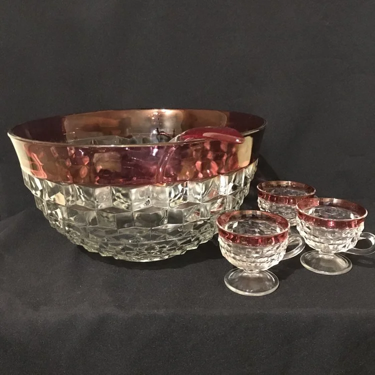 Ruby Rimmed Punch Bowl Cut glass with a ruffled cube pattern and a ruby glass rim with ladle. Comes with 12 matching cups with pedestal bases. 13.25" round x 7" tall. True Mid-century beauty.