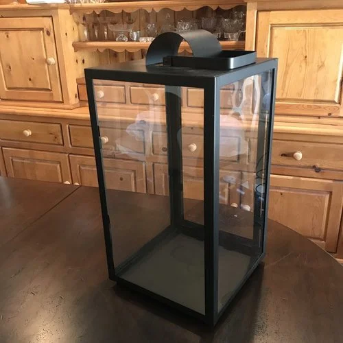 Large Black Lantern Matte black metal lantern with glass sides. Openable door on one side. Handle can be used for hanging. 20" tall x 10" square. Comes with three candles in glass.