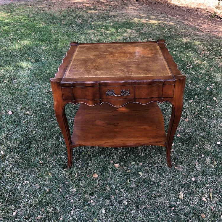 Sadie Scalloped, leather top table with one drawer. Gold details on the leather. Shelf on the bottom. 27" square x 25" high.