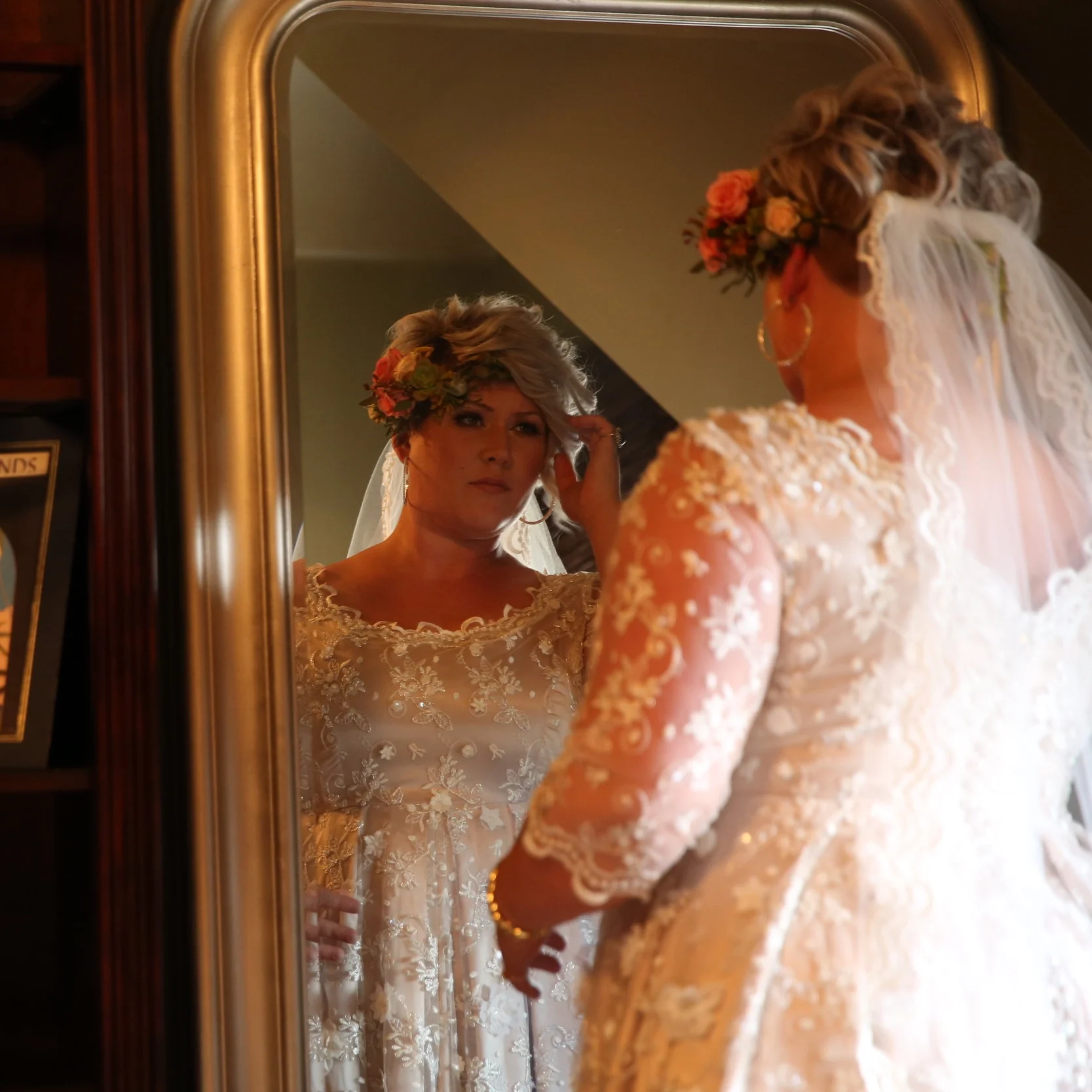 Bride looking at her reflection in the mirror as she contemplates her walk down the aisle to her groom.